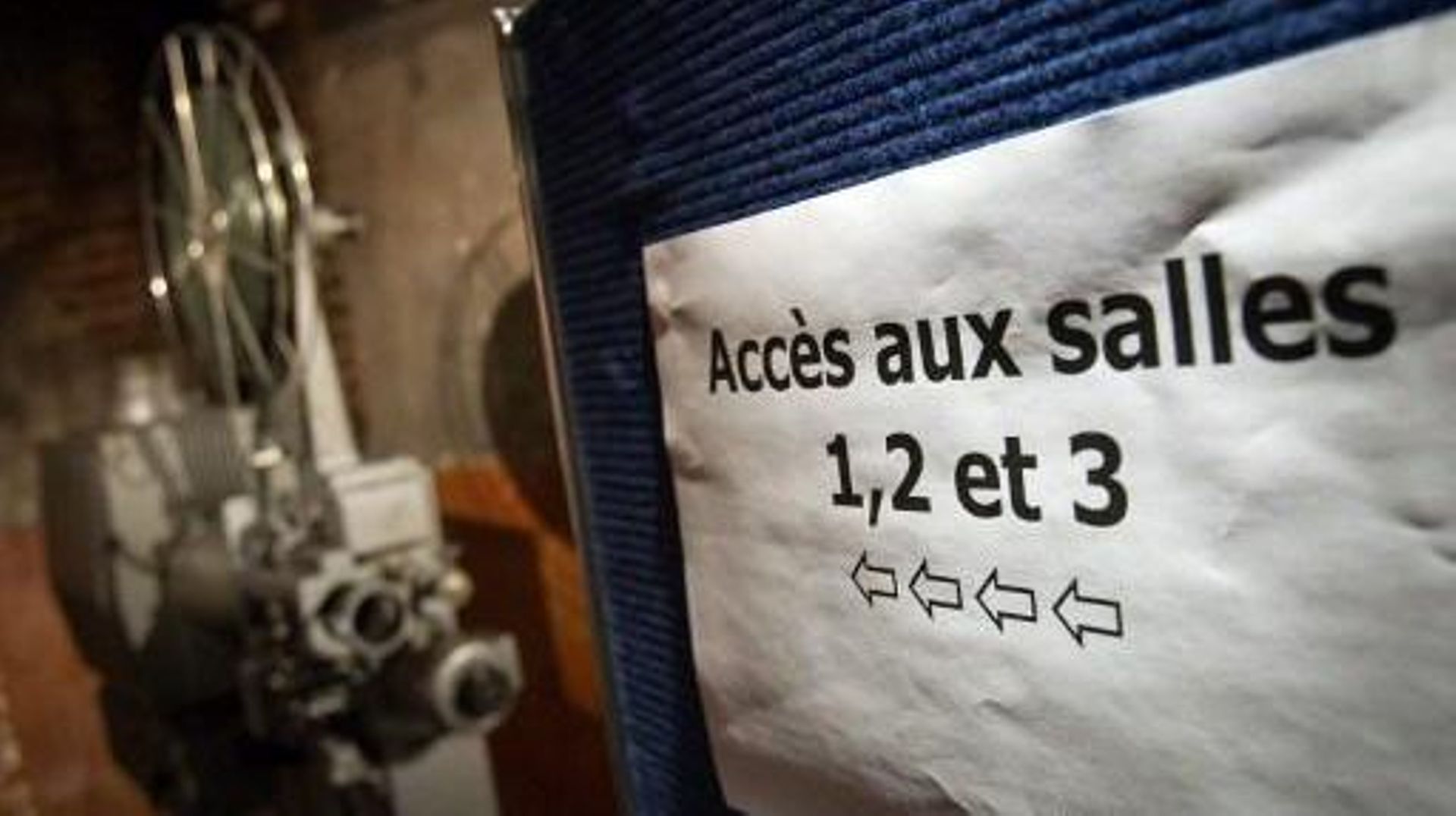 A picture taken on January 12, 2011 in Paris shows a film projector and a sign reading access to the screening rooms, at the Cinema des Cineastes movie theater.   AFP PHOTO LOIC VENANCE