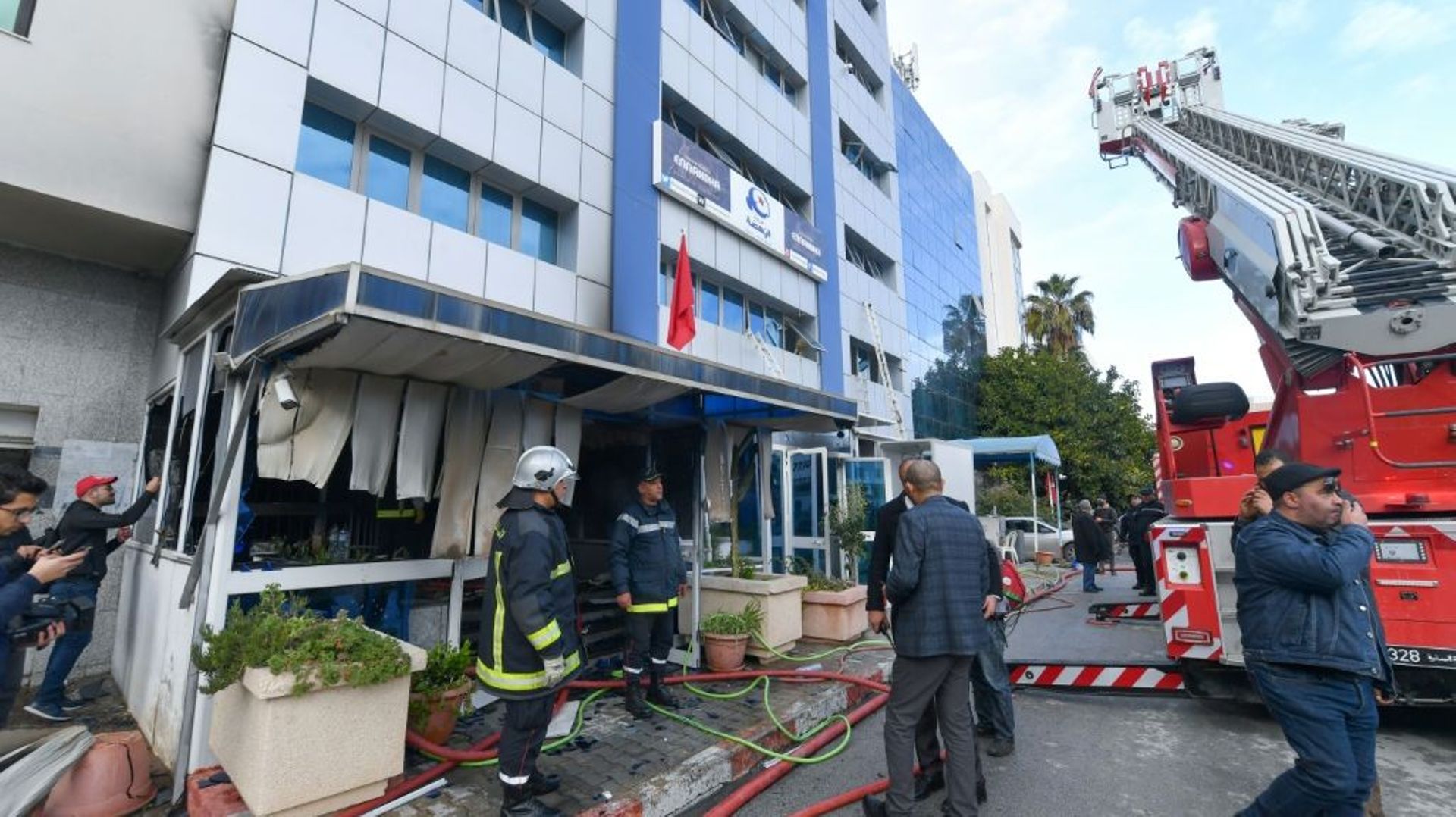 Des pompiers tunisiens en train d'éteindre le feu dans le siège du parti d'inspiration islamiste Ennahdha à Tunis le 9 décembre 2021 qui a fait un mort et 18 blessés