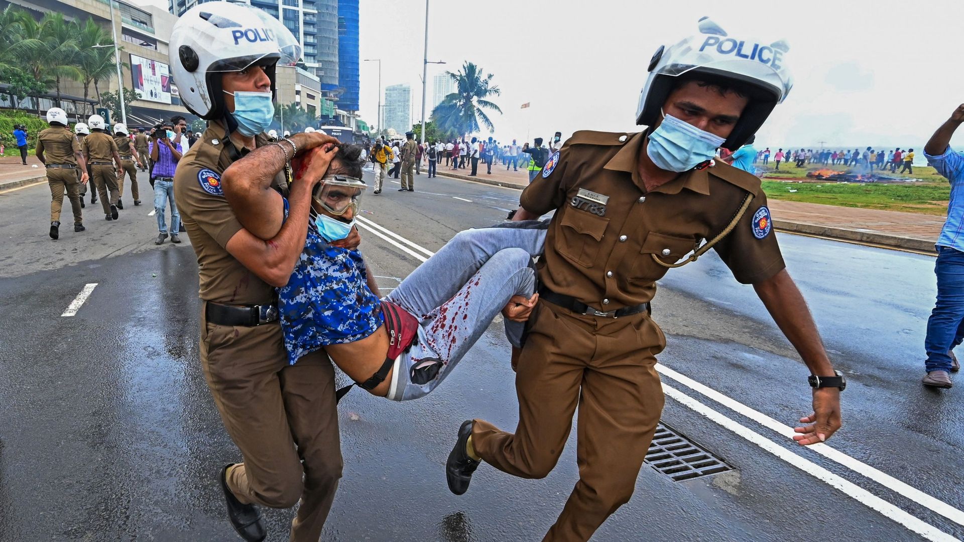 Des policiers portent un homme blessé pendant des affrontements entre des partisans du gouvernement et des manifestants devant le bureau du Président à Colombo, ce 9 mai 2022.