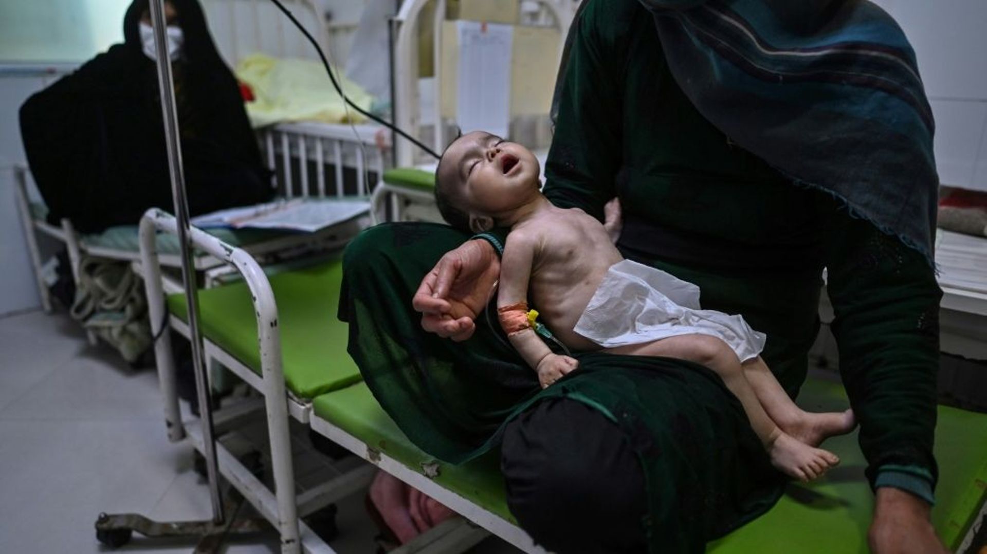 Une mère tient son enfant souffrant de malnutrition, mis sous perfusion dans une clinique de Médecins sans Frontières à Hérat, en Afghanistan, le 22 novembre 2021 