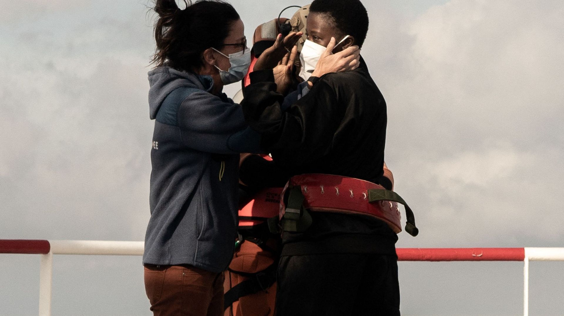 Une migrante nécessitant des soins médicaux urgents (à droite) fait un signe d’adieu alors qu’elle est sur le point d’être hélitreuillée par un hélicoptère de l’armée française depuis le navire de sauvetage Ocean Viking, le 10 novembre 2022, dans la mer T
