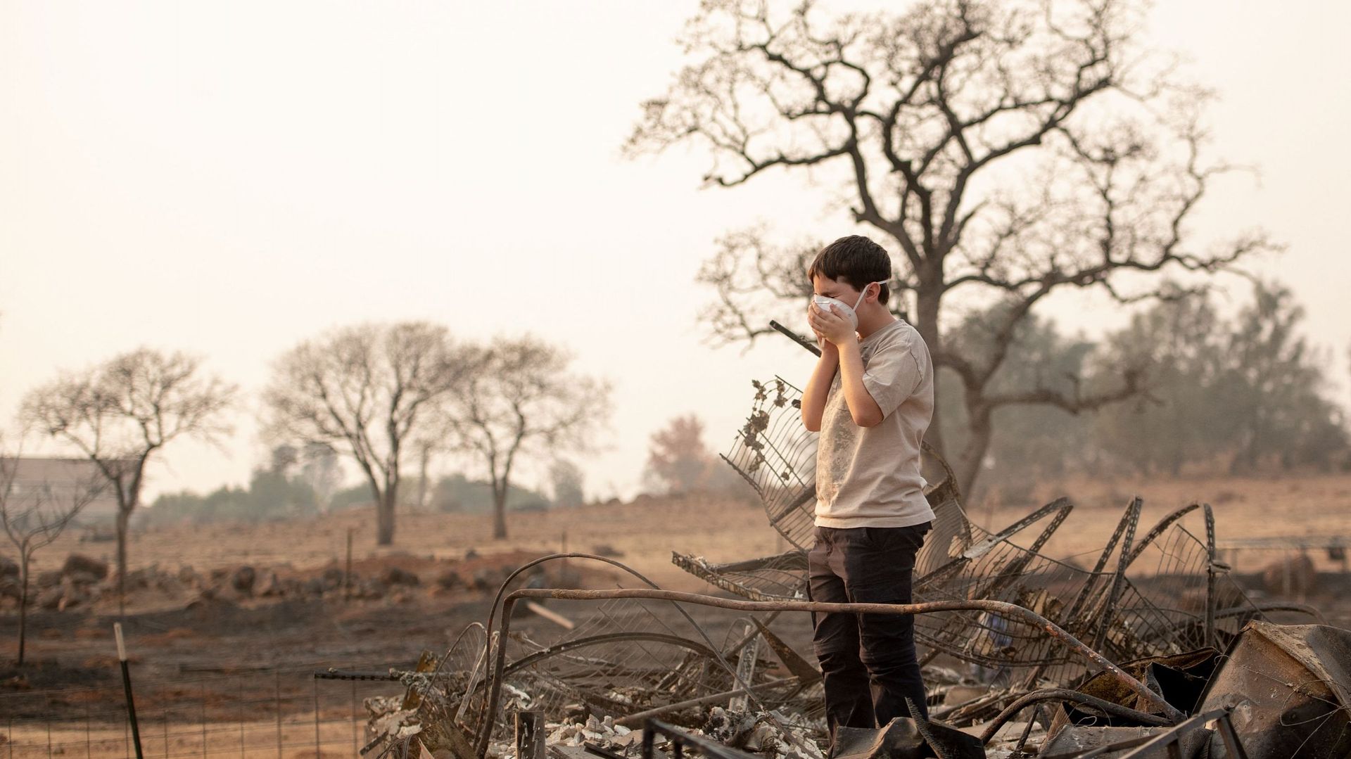 Jeremie Saylors, 11 ans, ajuste son masque de protection en fouillant les restes brûlés de sa maison à Paradise, en Californie, le 18 novembre 2018