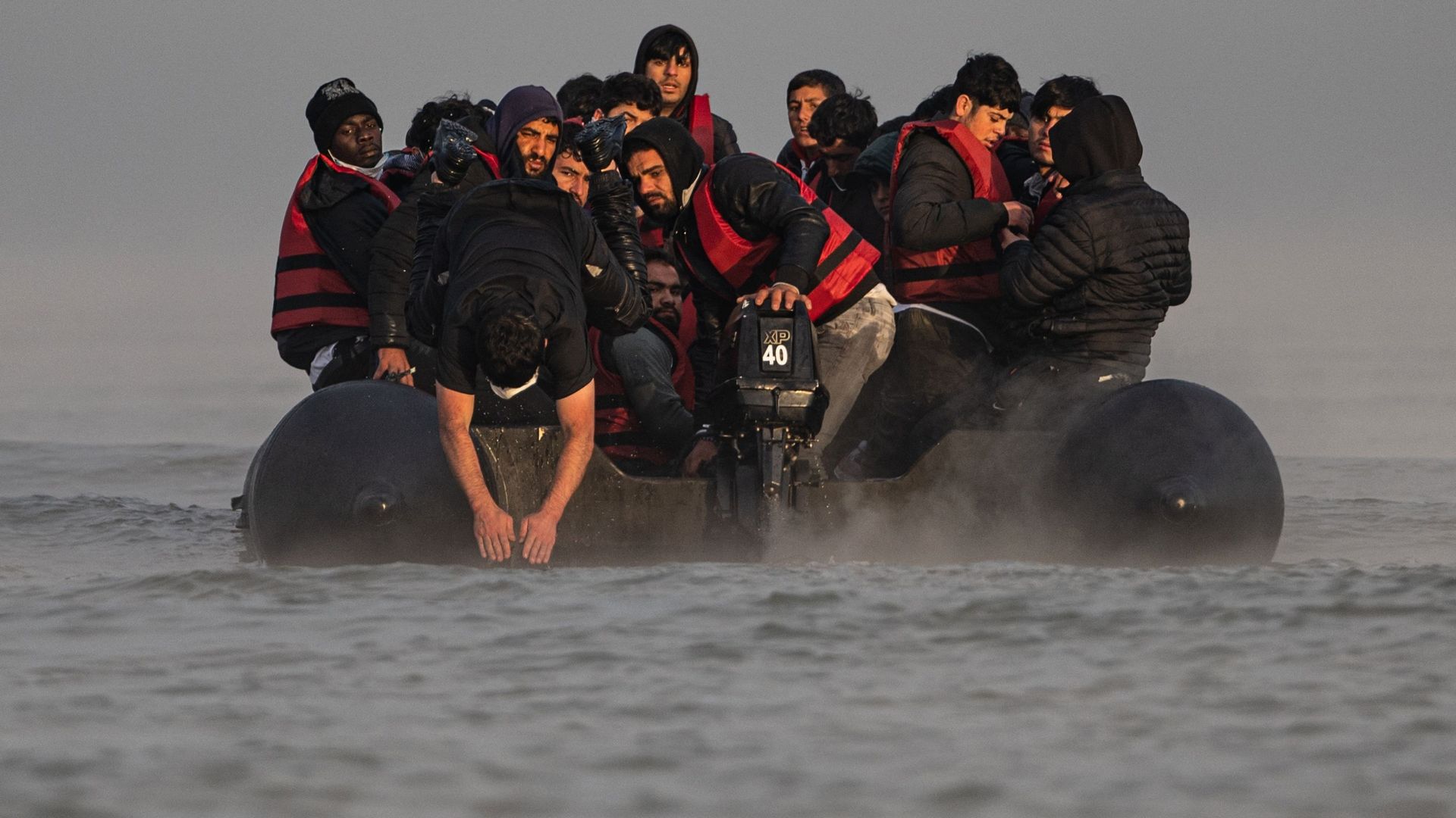 Un passeur saute dans l’eau après avoir embarqué des migrants sur la plage de Gravelines, près de Dunkerque, dans le nord de la France, le 12 octobre 2022, pour tenter de traverser la Manche.