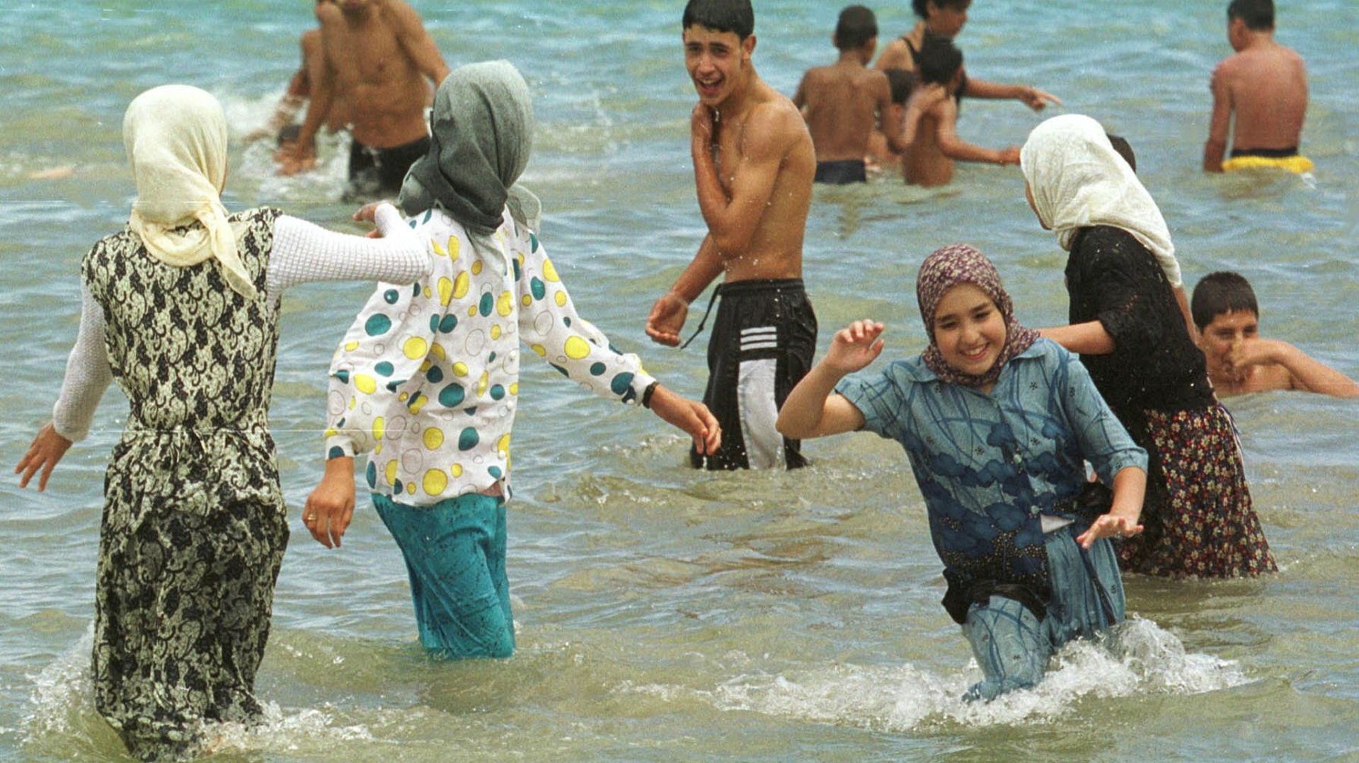 En 2000 déjà,des jeunes filles voilées plaisantent avec des jeunes hommes en maillot de bain, le 23 juillet 2000 sur la plage de Tanger. Obligés par les autorités marocaines de quitter leurs campings, les militants d'Al Adl Oualihsane (Justice et bienfais