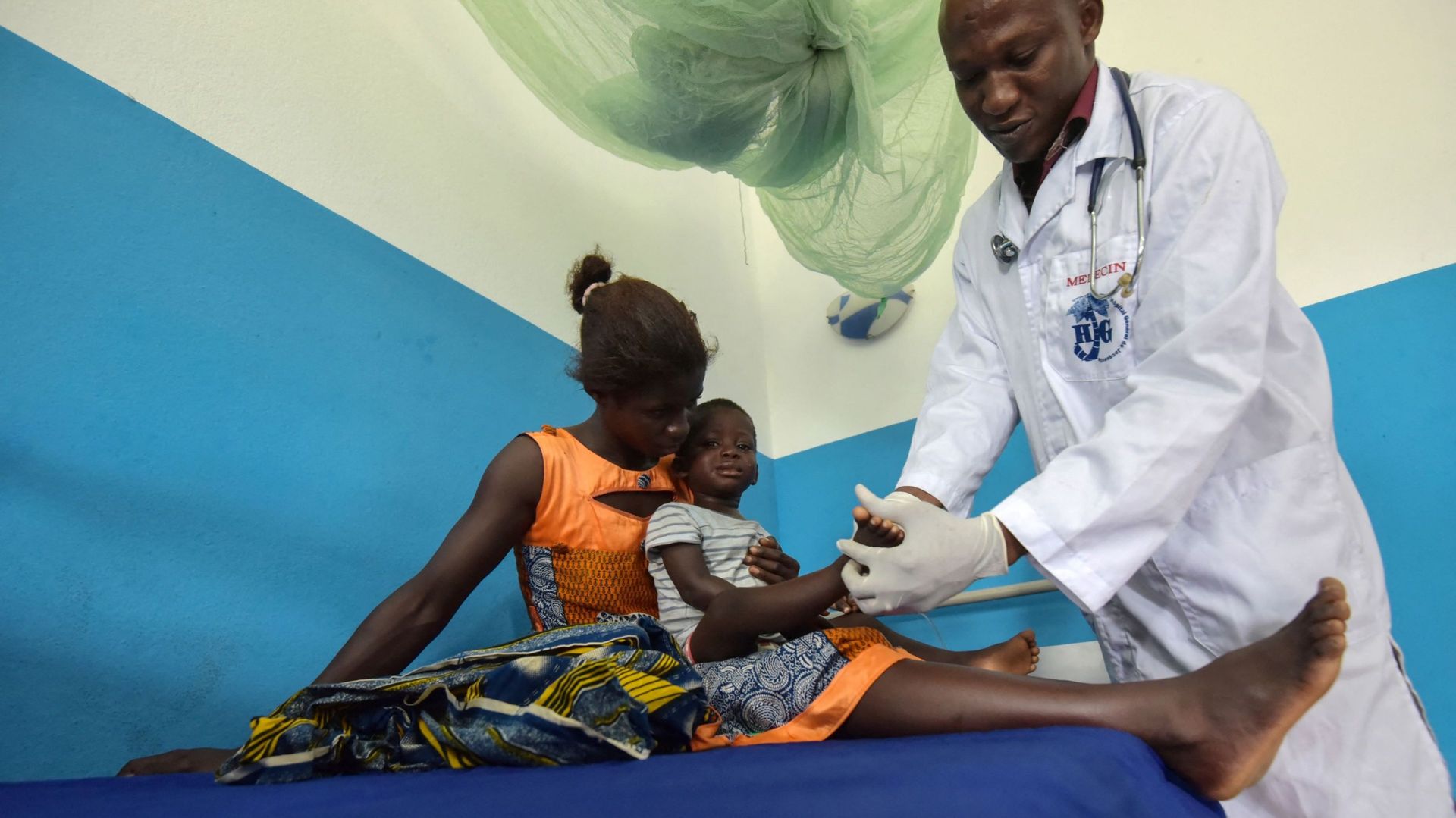 Une femme tient un enfant qui a contracté le paludisme et est examiné par un médecin à l'hôpital général de Jacqueville, à une vingtaine de kilomètres à l'ouest d'Abidjan, le 19 avril 2019. 
