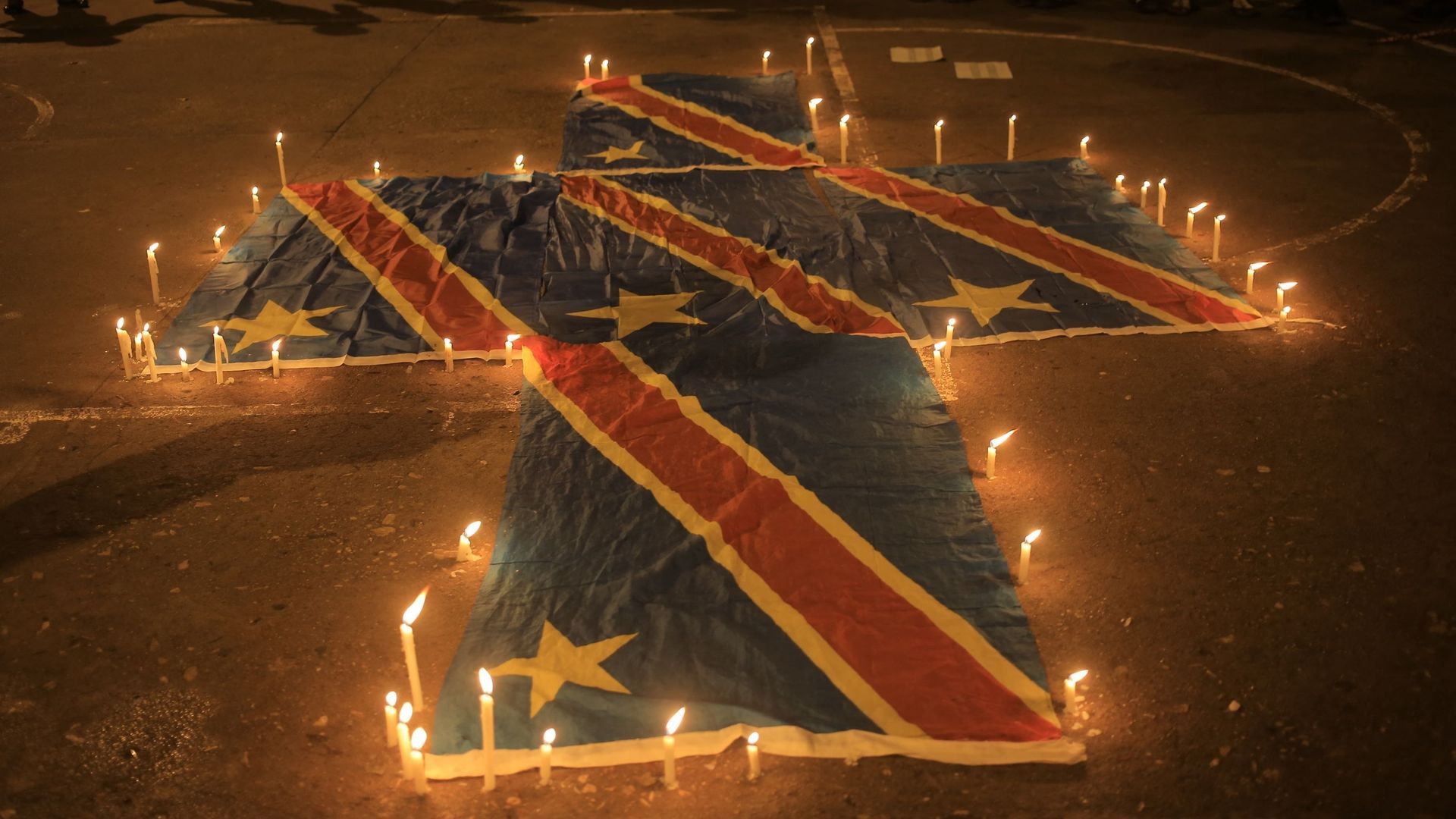 Des drapeaux de la République démocratique du Congo entourés de cierges à Béni lors d’une veillée commémorative des massacres des 29 et 30 novembre – 131 victimes – attribués au M23.
