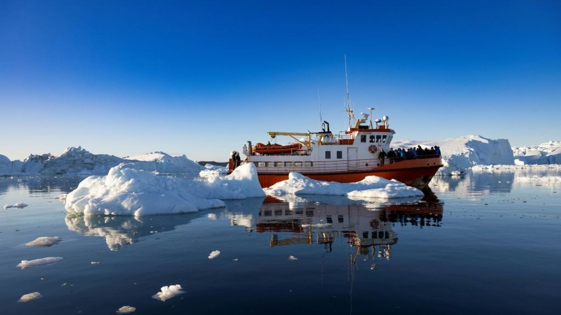 Un bateau de touristes au milieu des icebergs dans la baie de Disko, le 1er juillet 2022 à Ilulissat, au Groenland