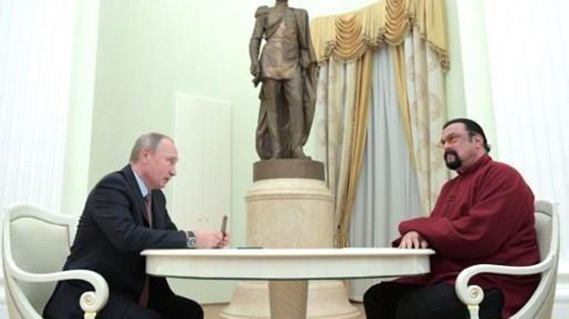 Russian President Vladimir Putin (L) holds a Russian passport before presenting it to US action hero actor Steven Seagal during a meeting at the Kremlin in Moscow on November 25, 2016.
Alexey DRUZHININ / SPUTNIK / AFP