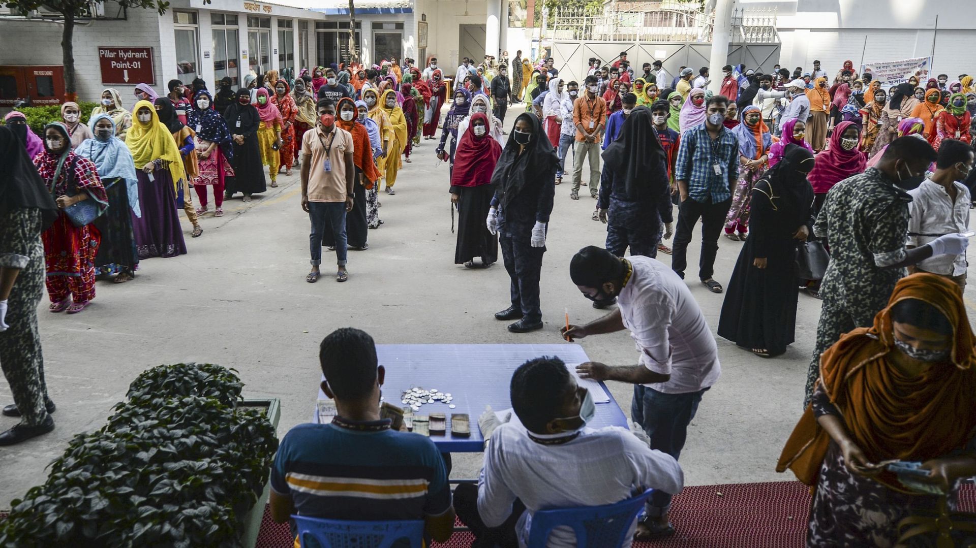 Des ouvriers font la queue pour toucher leur salaire dans une usine de confection pendant le lockdown imposé par le gouvernement à titre de mesure préventive contre le coronavirus COVID-19 à Savar, dans la banlieue de Dhaka, la capitale du Bangladesh, le