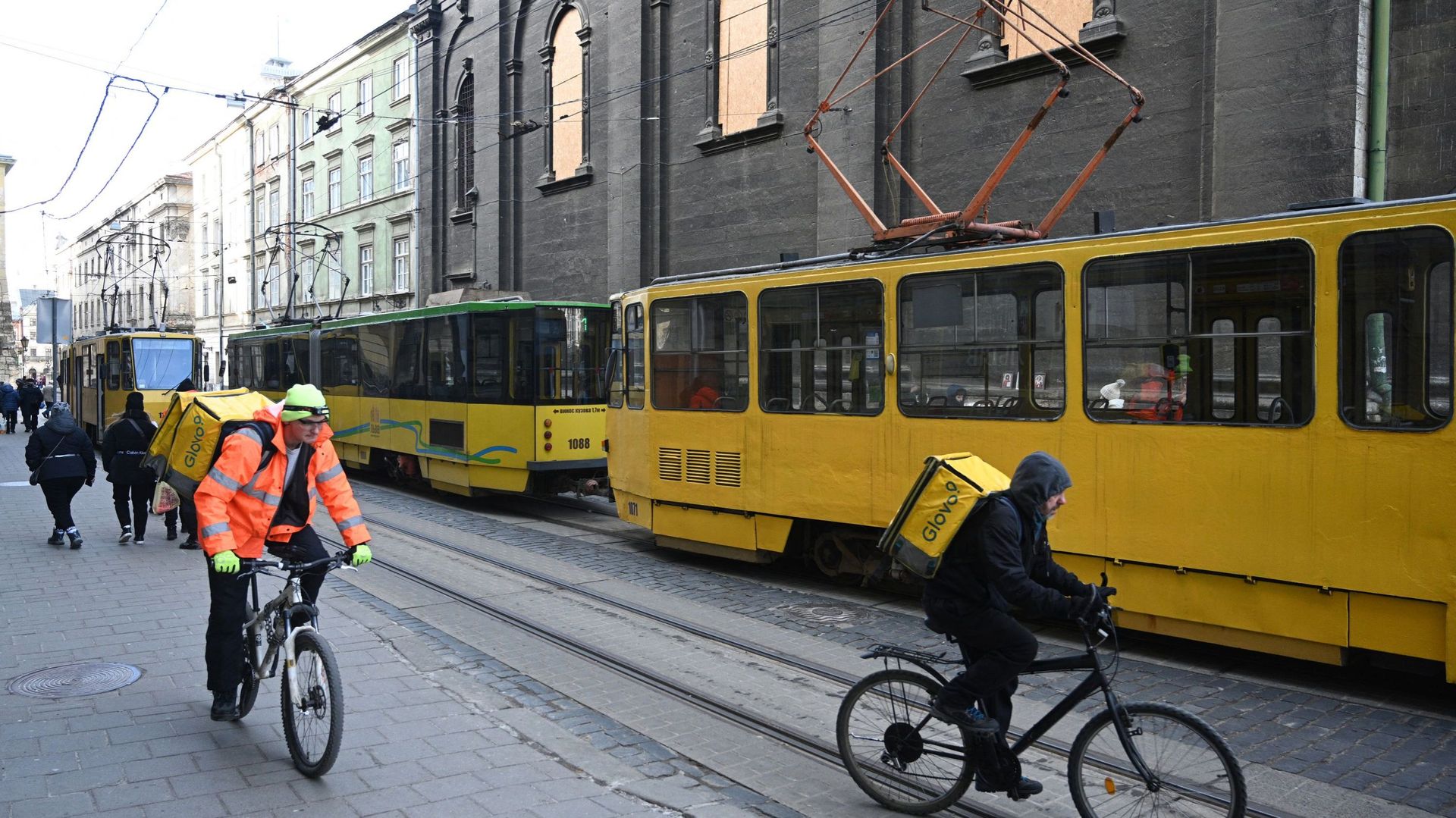 Des cyclistes passent à côté de deux rames de tramway bloqués par les coupures de courant à Lviv.