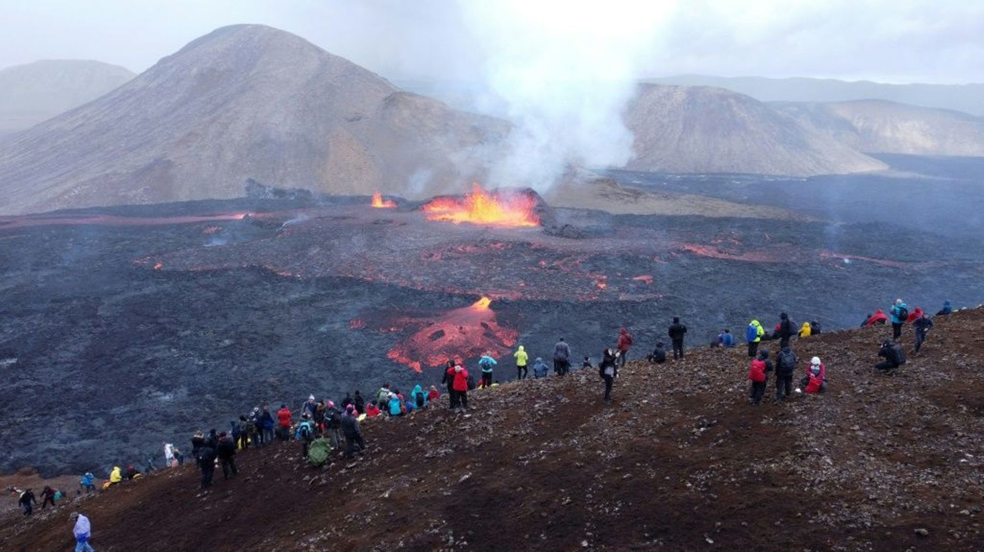 Des curieux admirent la lave qui s'échappe d'un cratère dans la vallée de Meradalir, près de Reykjavik, en Islande, le 10 août 2022