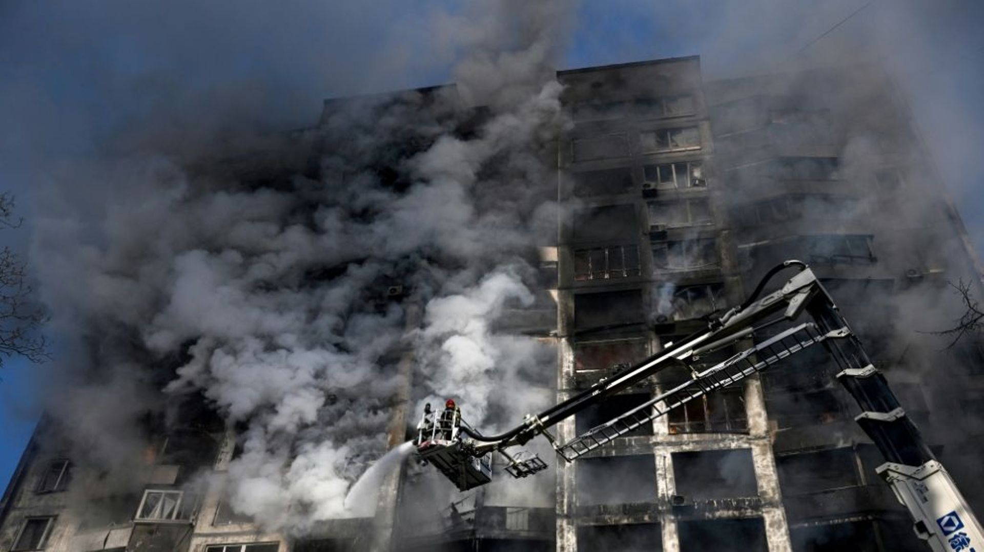 Des pompiers sur une grue éteignent un incendie dans un immeuble résidentiel, à Kiev le 15 mars 2022
