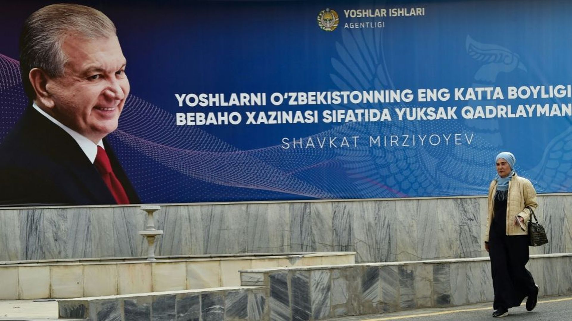 Une femme passe le 20 octobre 2021 à Tachkent devant une affiche de campagne du président de l'Ouzbékistan Chavkat Mirzioïev, réélu dimanche