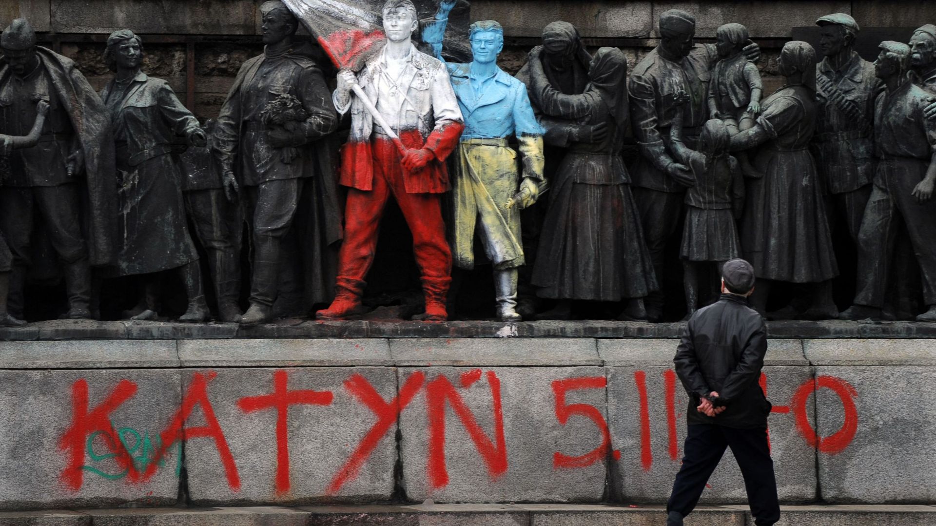 Un homme regarde les figures de soldats communistes, peintes aux couleurs des drapeaux ukrainien et polonais par un artiste inconnu et avec des panneaux "Katyn 5.03.1940" dans le centre de Sofia, le 5 mars 2014.