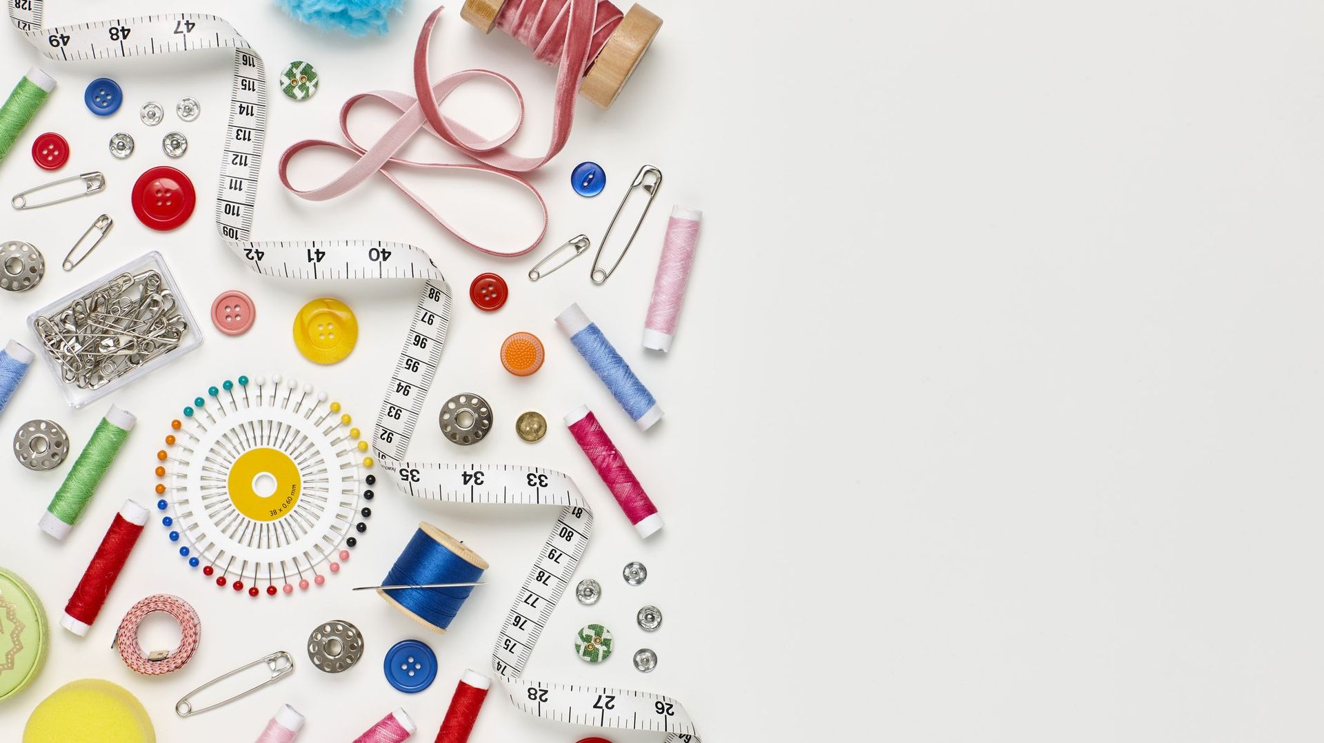 Overhead flat lay of colorful sewing items on white background