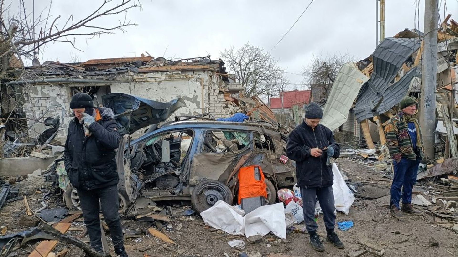 Trois hommes devant des ruines provoquées par un bombardement des forces russes à Jitomir, en Ukraine, le 2 mars 2022