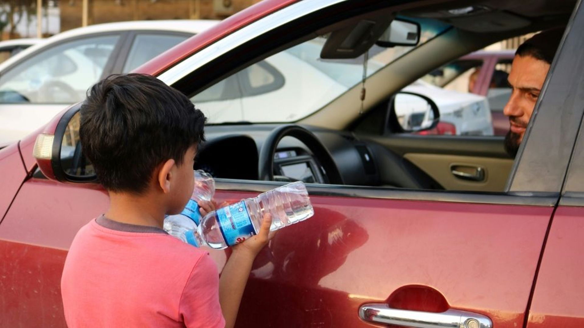 Un garçon irakien essaye de vendre des bouteilles d'eau dans une rue de Mossoul, où des enfants orphelins errent pour mendier ou vendre des objets futiles pour survivre, un an après la reprise par l'armée irakienne de la ville aux jihadistes, le 7 juillet