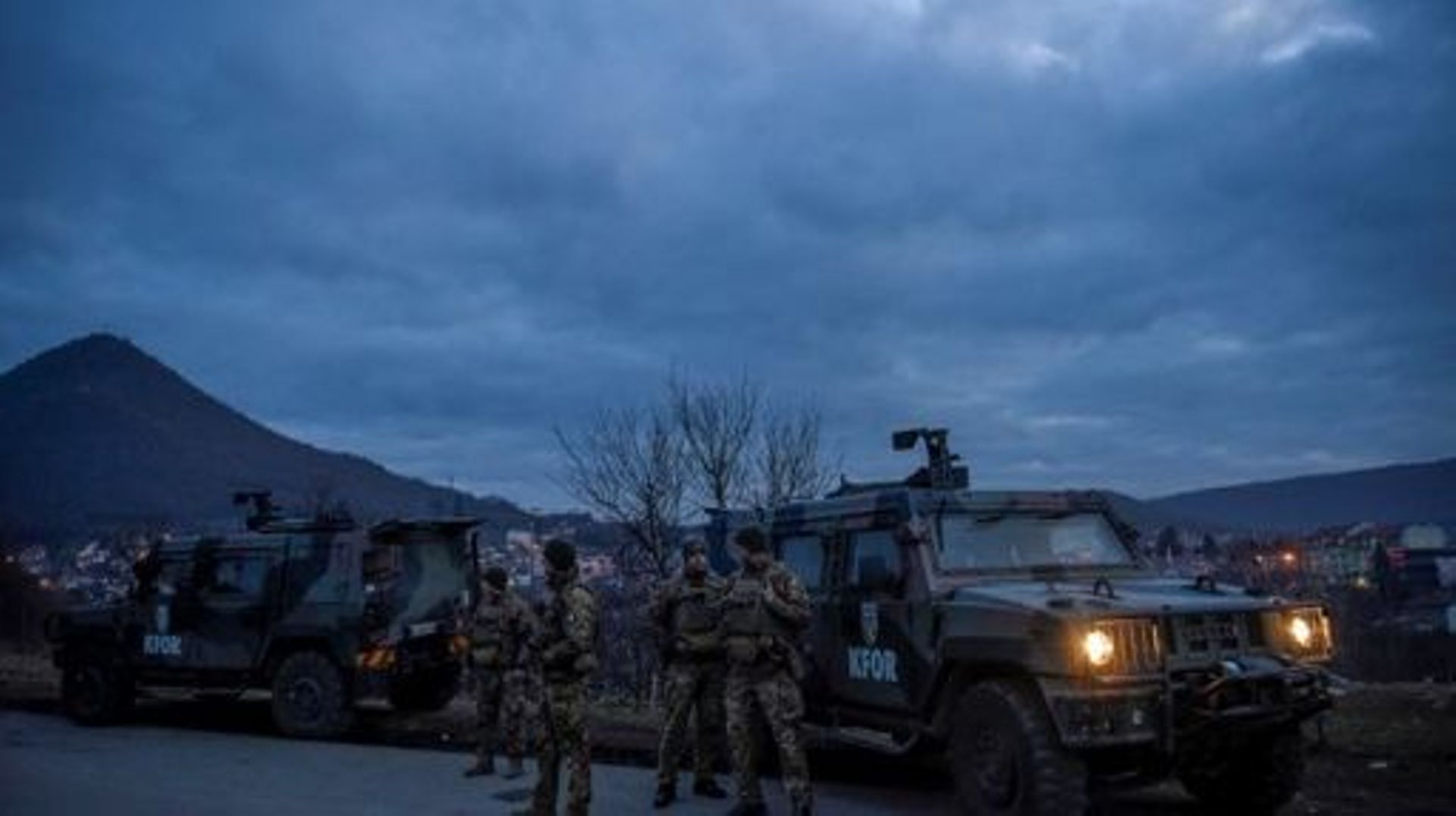 Des soldats de l’OTAN participant à une mission de maintien de la paix au Kosovo (KFOR) patrouillent pendant que des Serbes du Kosovo enlèvent des camions d’une barricade routière érigée par des Serbes de souche dans le village de Rudare, près de la ville