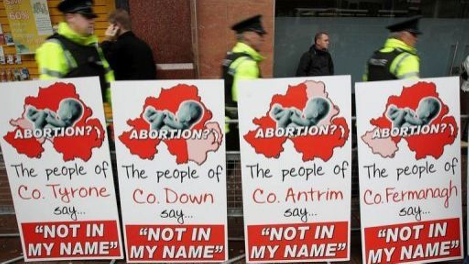 Des policiers marchent près d'affiches placardées par des opposants à l'avortement, le 18 octobre 2012 à Belfast