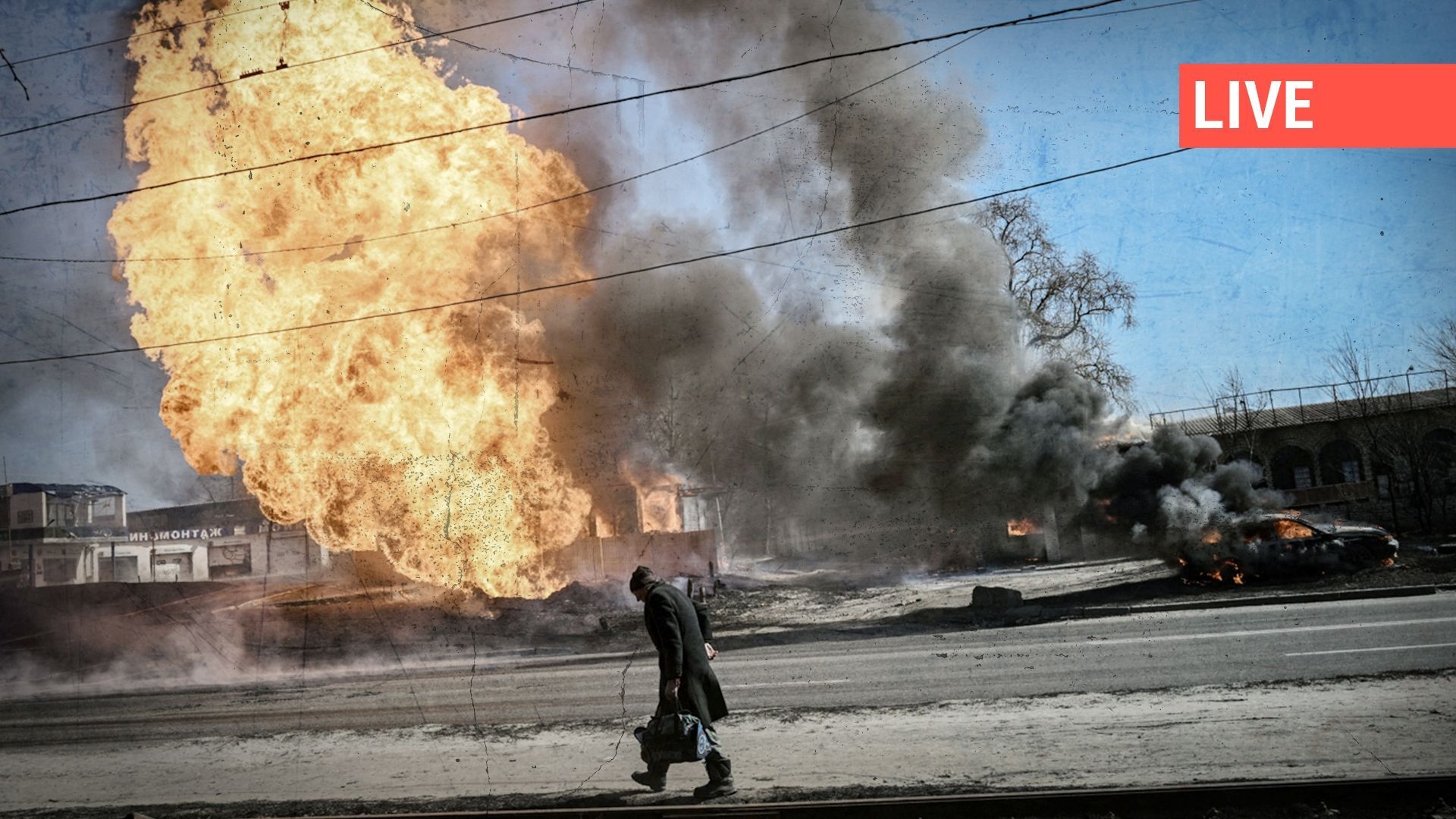Ukrainienne passant devant des flammes et de la fumée s'élevant d'un incendie après un tir d'artillerie à Kharkiv, le 25 mars.