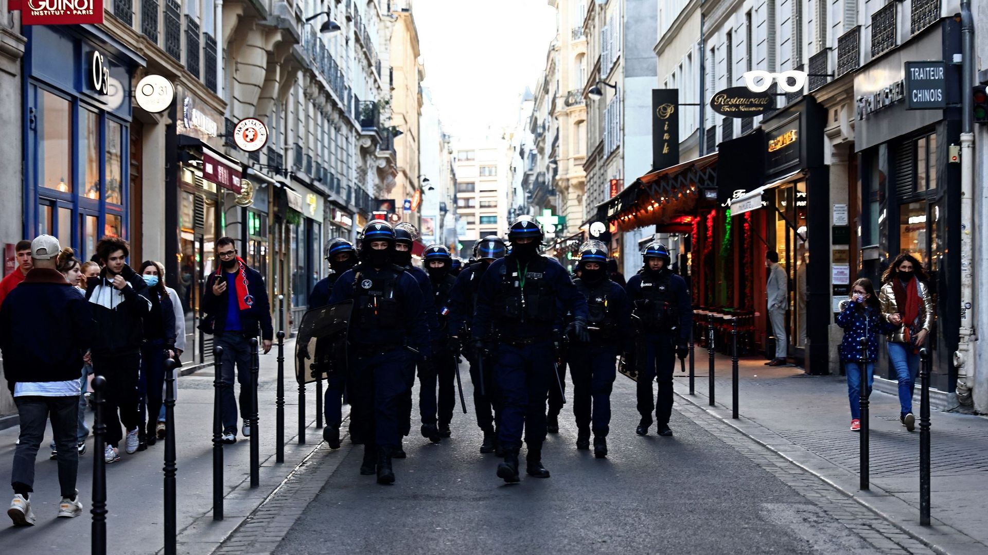 Des policiers antiémeutes français marchent dans une rue de Paris parmi des passants, le 12 février 2022, alors que des convois de manifestants appelés "Convoi de la Liberté" arrivent dans la capitale française.