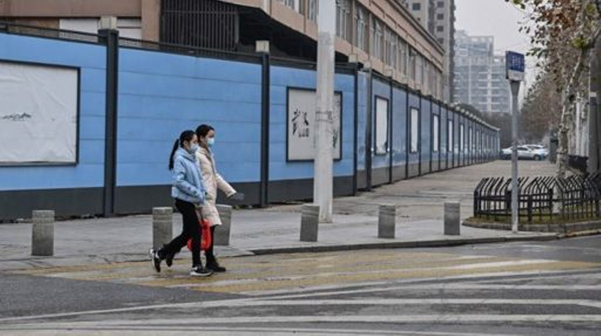 Des personnes marchent à côté du marché de gros de fruits de mer Huanan, fermé, où le coronavirus Covid-19 a été détecté pour la première fois, à Wuhan, le 22 janvier 2023.