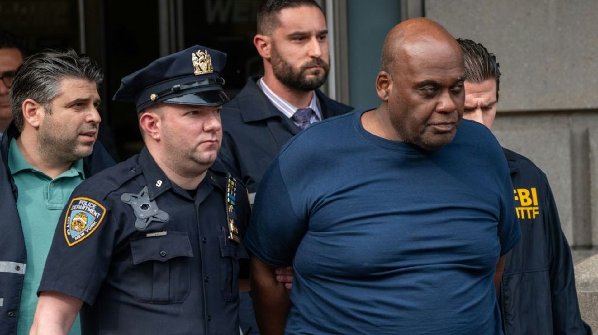 Frank Jmes (c) soupçonné d’avoir tiré dans le métro de New York, escorté par des policiers peu après son arrestation, le 13 avril 2022