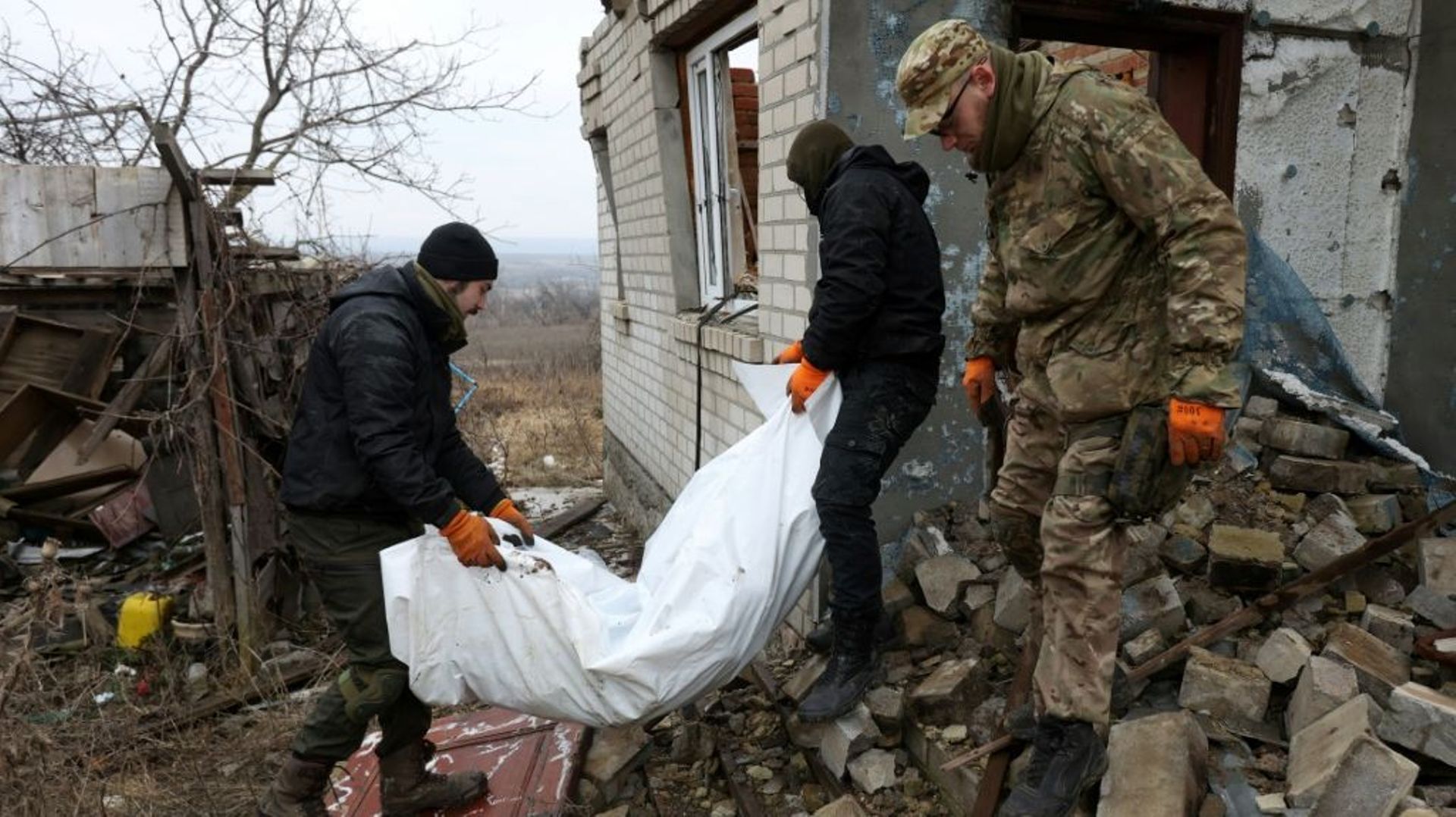 Des bénévoles ukrainiens portent le corps d'un soldat russe tué dans les combats, qu'ils viennent d'exhumer, le 18 janvier 2023 à Dolina, dans la région de Donetsk