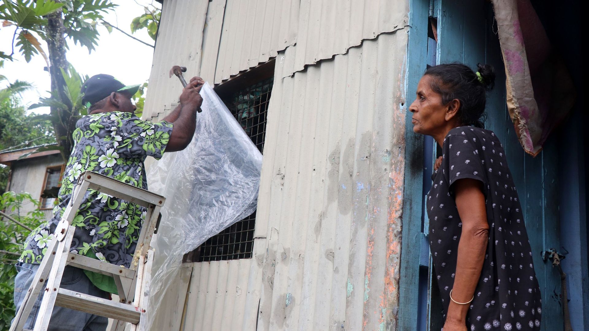 Un habitant sécurise sa maison en plaçant des bâches en plastique sur les fenêtres avant l'arrivée du super cyclone Yasa à Suva, la capitale des Fidji, le 16 décembre 2020.