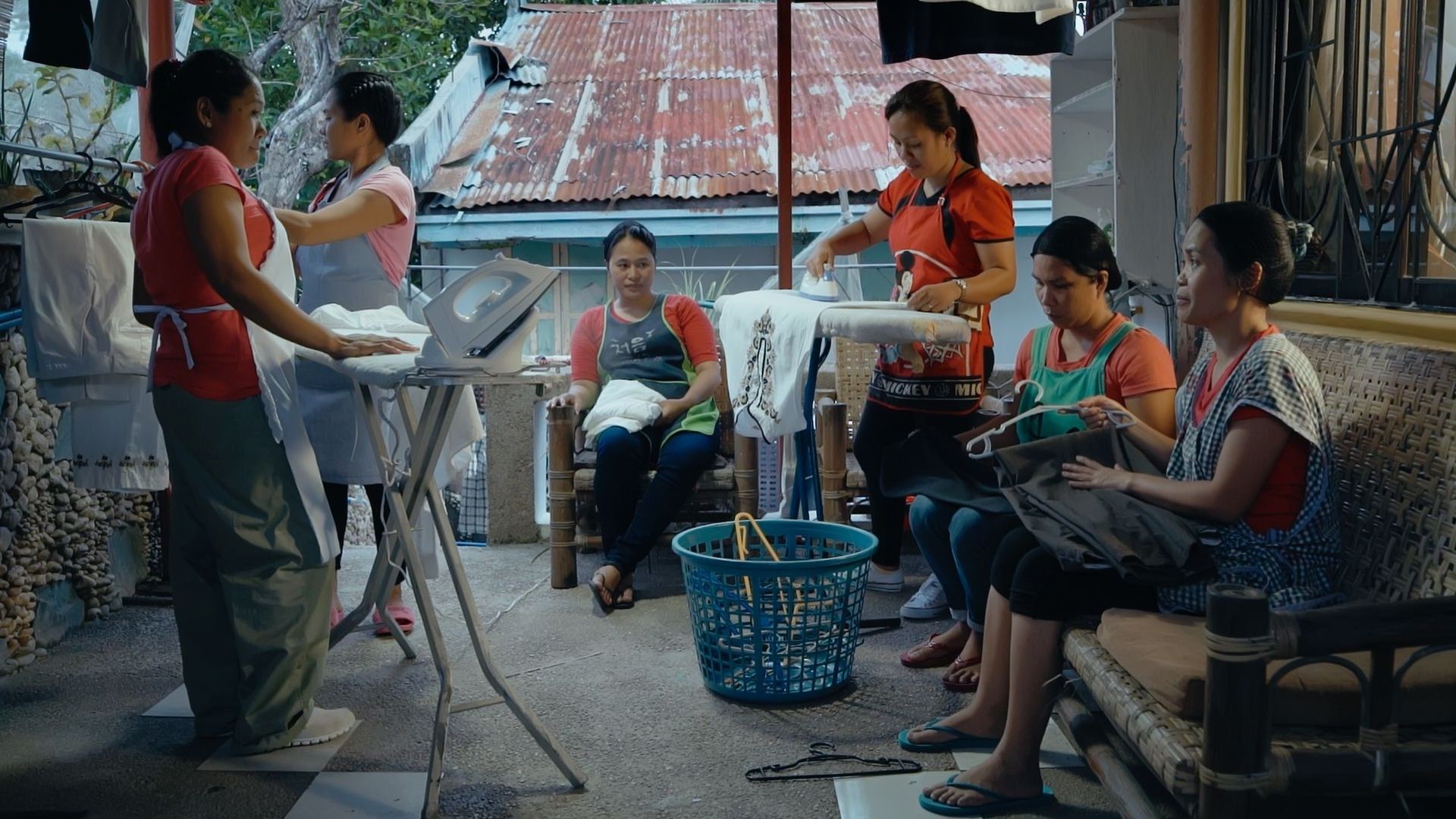 Image extraite du film documentaire "Overseas" de Sung-A Yoon. Plusieurs femmes philippines travaillent et font du repassage dans une petite pièce.