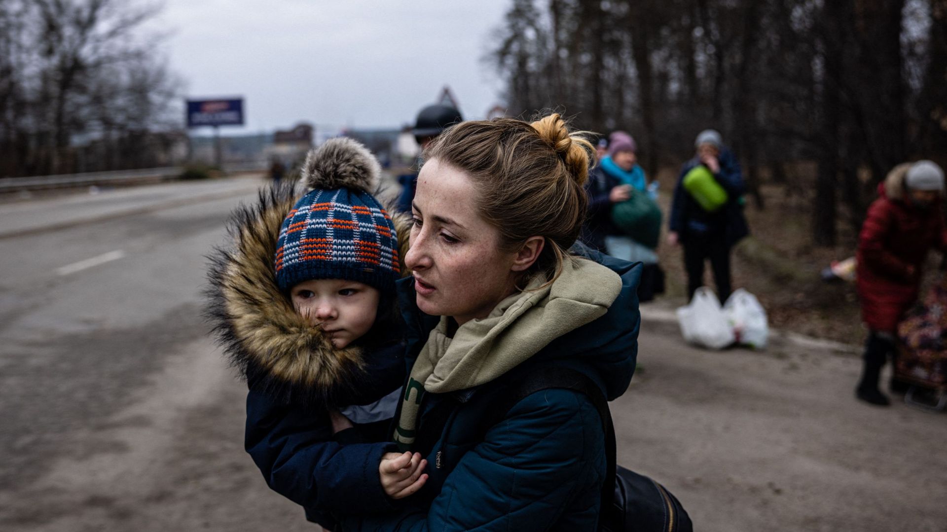 Une femme porte son enfant alors qu’ils fuient les combats et les bombardements russes dans la ville d’Irpin, au nord-ouest de Kiev.