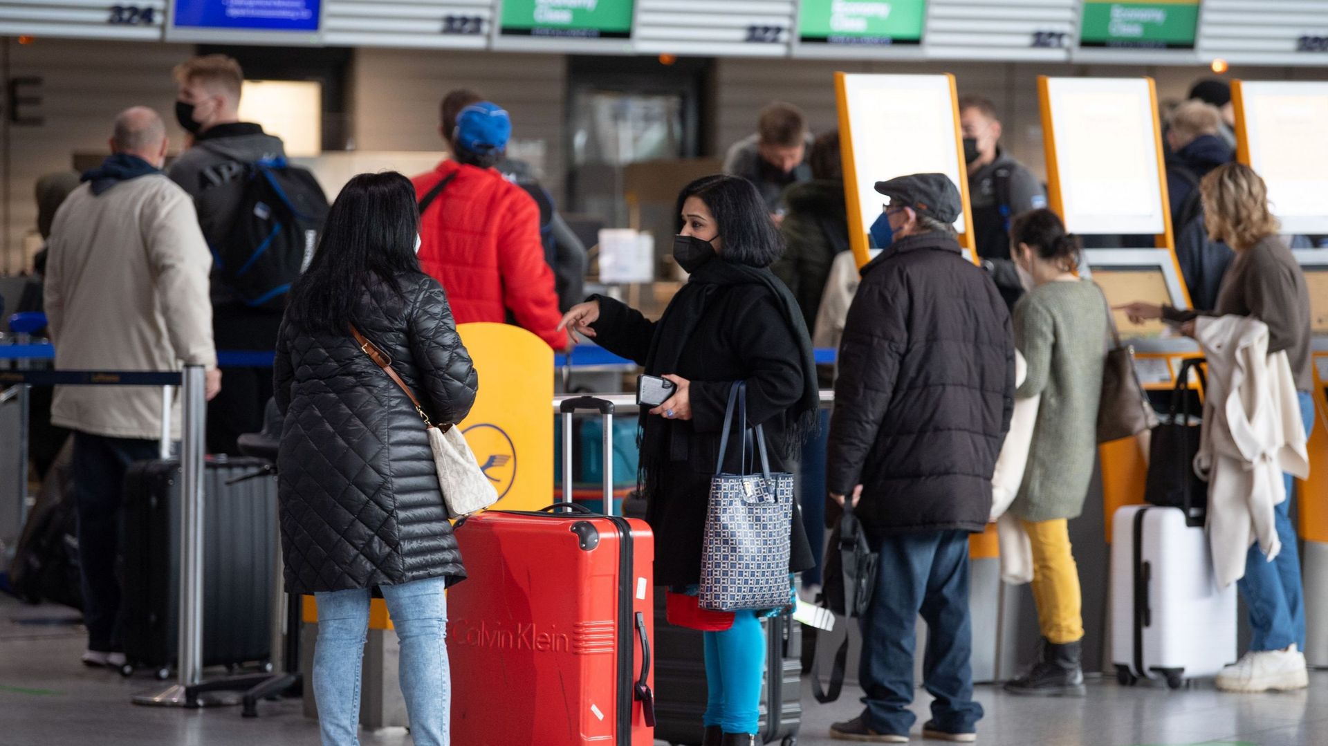 Des passagers attendent devant les comptoirs d'enregistrement de l'aéroport de Francfort le 26 novembre 2021