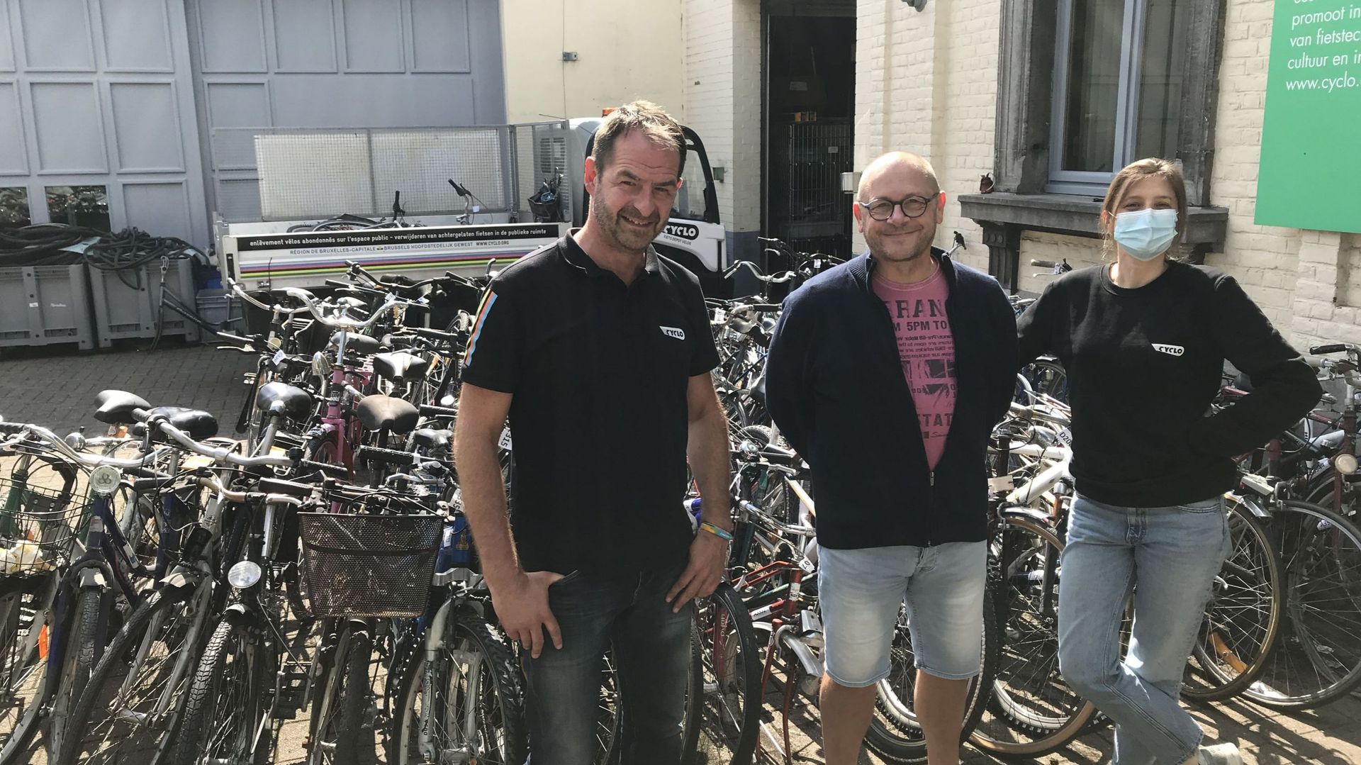 Michaël, Eric et Caroline, une partie de l'équipe de l'ASBL Cyclo devant une partie des vélos en "résidence" dans leur dépôt-atelier de Schaerbeek