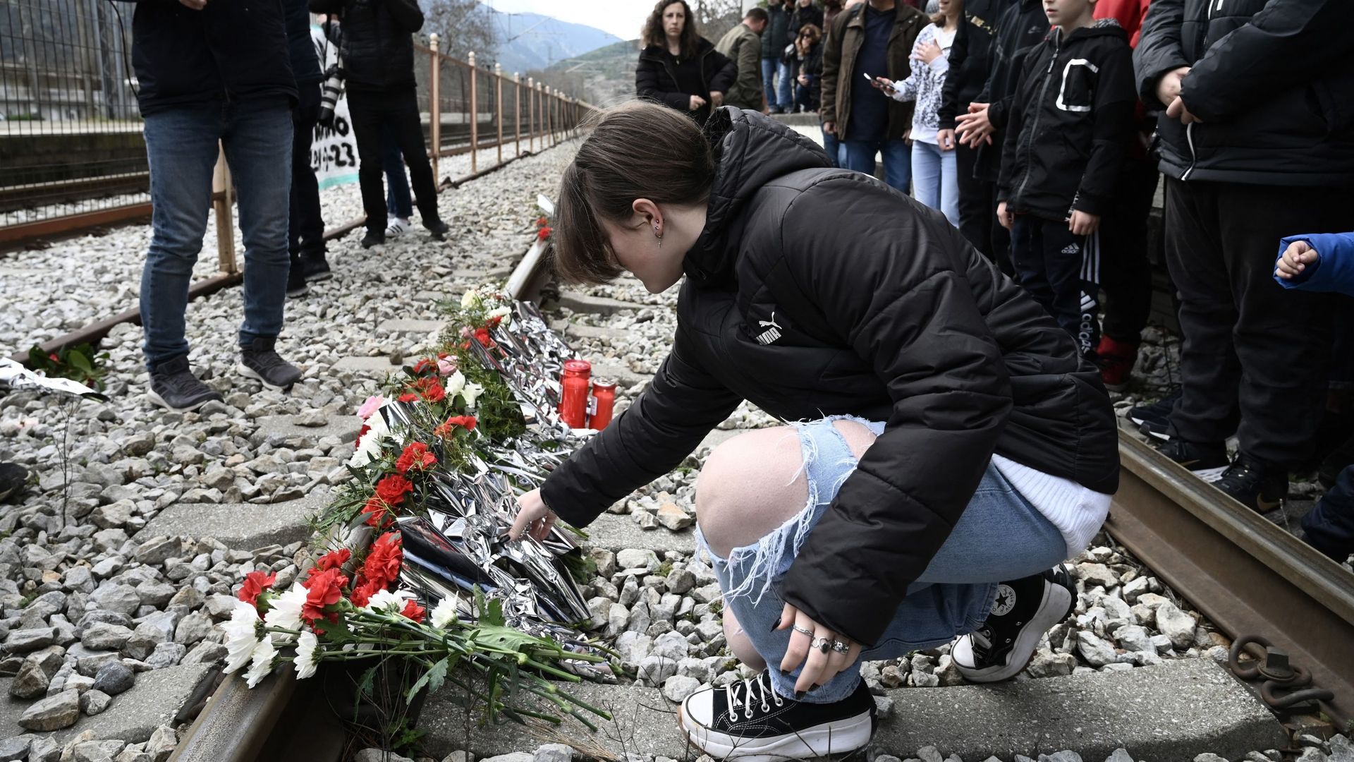 Un jeune dépose des fleurs sur les voies à la gare de Rapsani, dans le nord de la Grèce, le 5 mars 2023, lors d'un rassemblement commémoratif pour les victimes d'un accident de train mortel qui a tué 57 personnes.