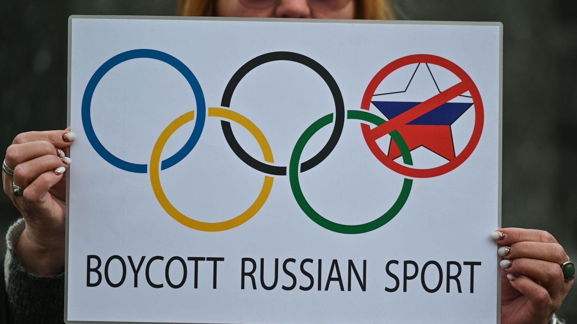 Une manifestante à Cracovie tient une affiche liée aux Jeux olympiques d'été à Paris et les mots "Boycott du sport russe", le 31 mars 2023.