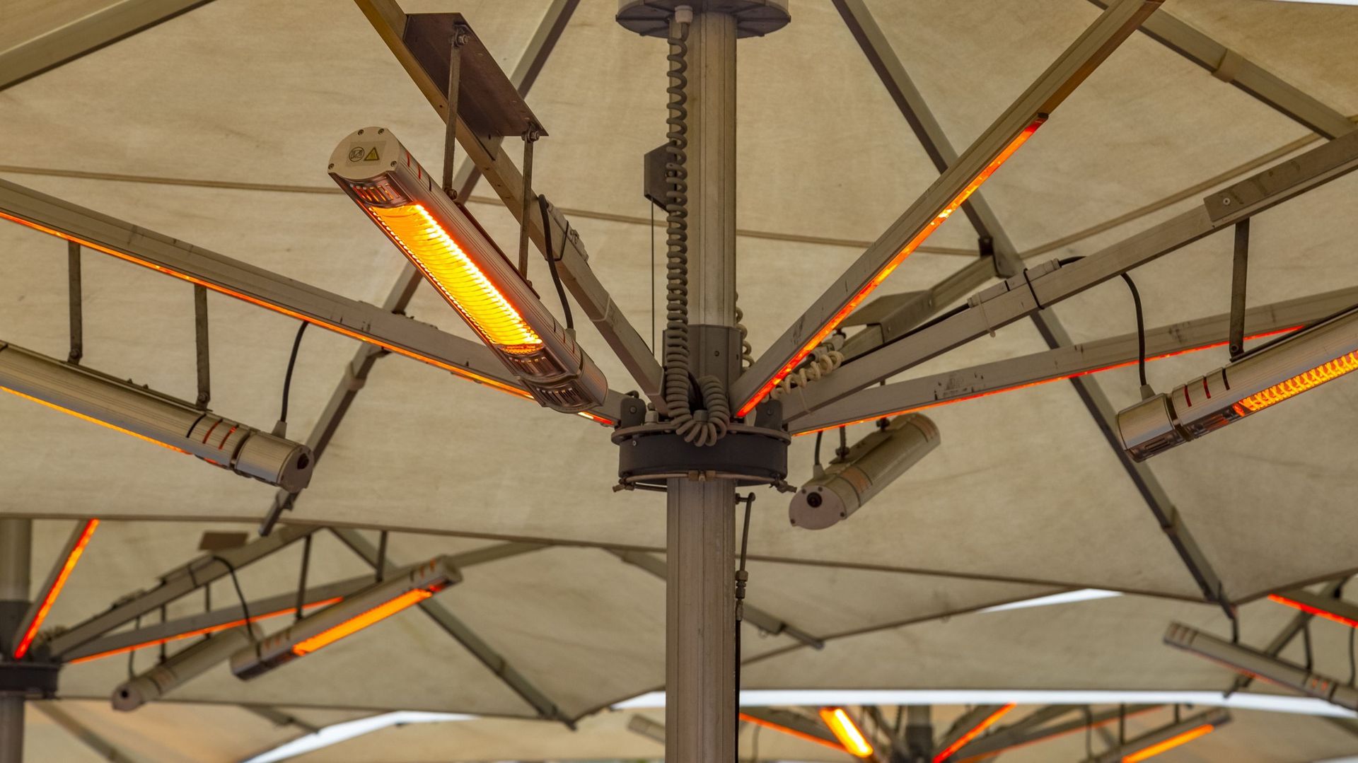 Lampes infrarouges électriques extérieures de chauffage sous parapluie à une terrasse de café en hiver.