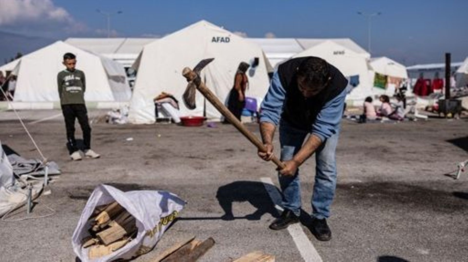 Abit Sertel cuts firewood next to his tent in a makeshift camp next to the new Hatay stadium in Antakya, southern Turkey, on February 22, 2023. A 6.4-magnitude earthquake has rocked Turkey’s southern province of Hatay and northern Syria, killing six peopl