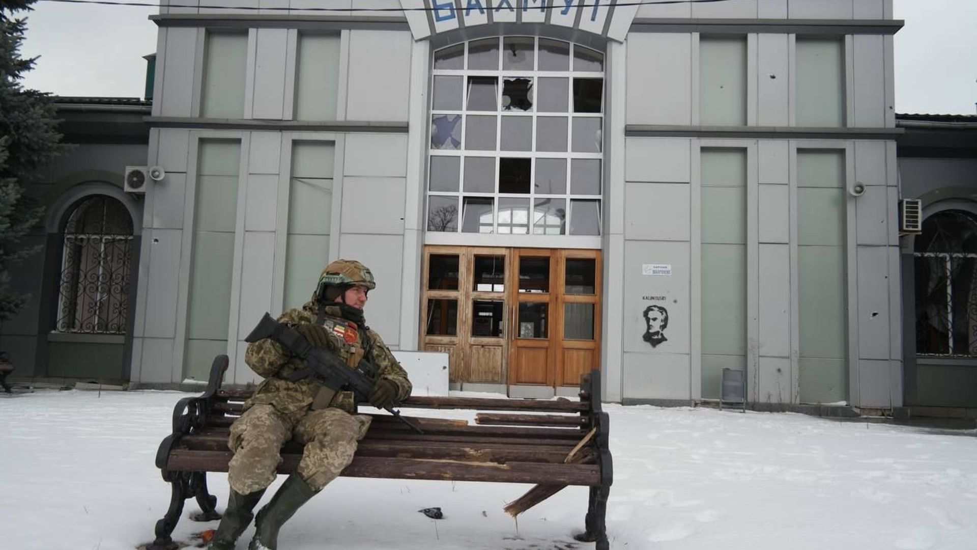 Un soldat biélorusse avec une arme belge devant un bâtiment à Bakhmout