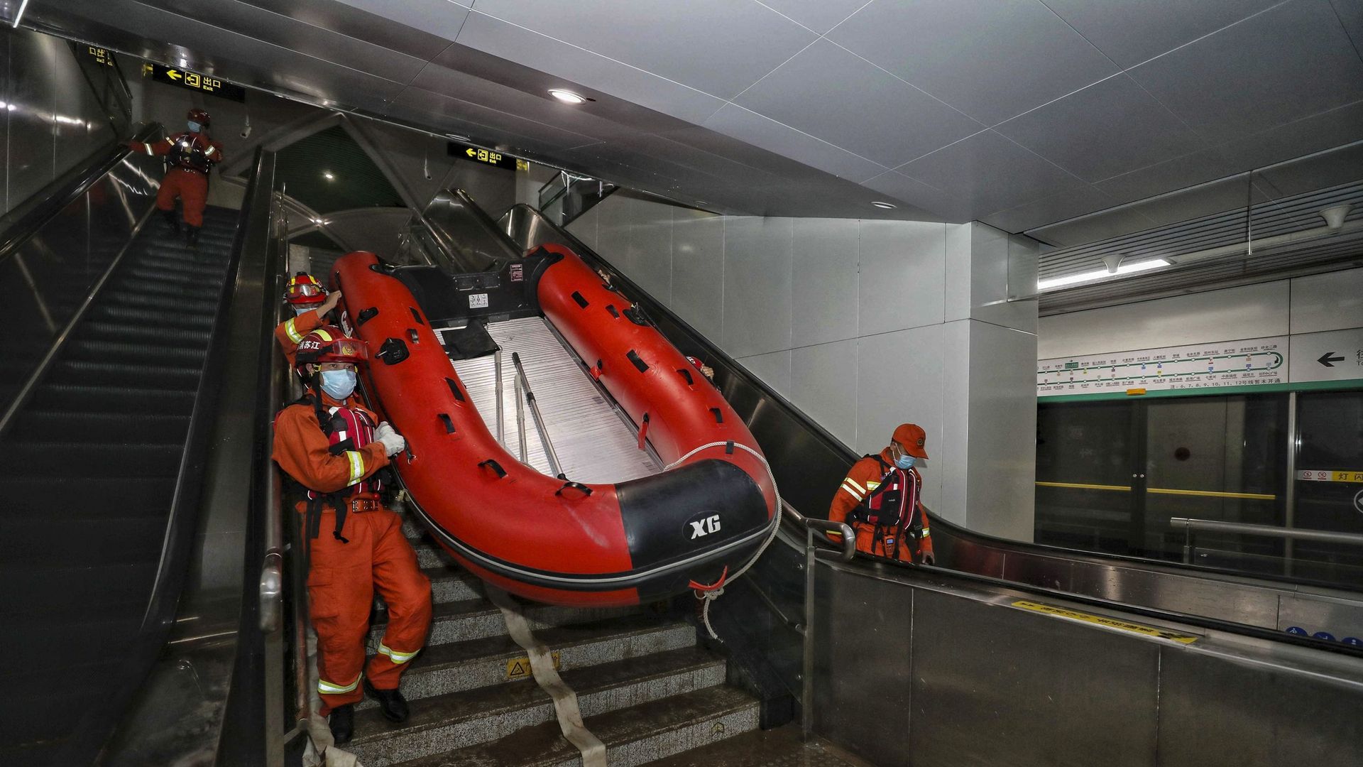 Les sauveteurs transportent un bateau alors qu’ils fouillent dans le métro inondé à la suite de fortes pluies à Zhengzhou.