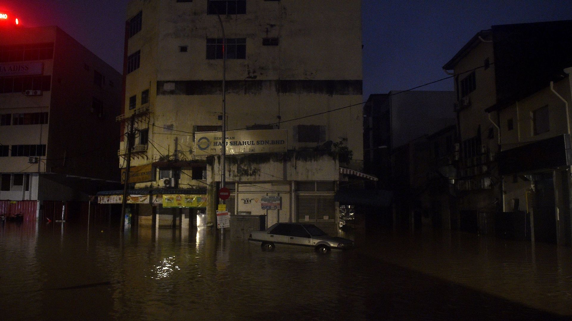 Une voiture est vue dans l'eau d'une inondation causée par de fortes pluies à Kuala Lumpur, tôt le 19 décembre 2021.