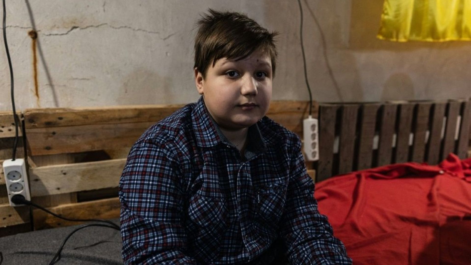 Volodymyr, 12 ans, joue avec son téléphone dans une cave à Bakhmout, dans l'est de l'Ukraine le 22  décembre 2022