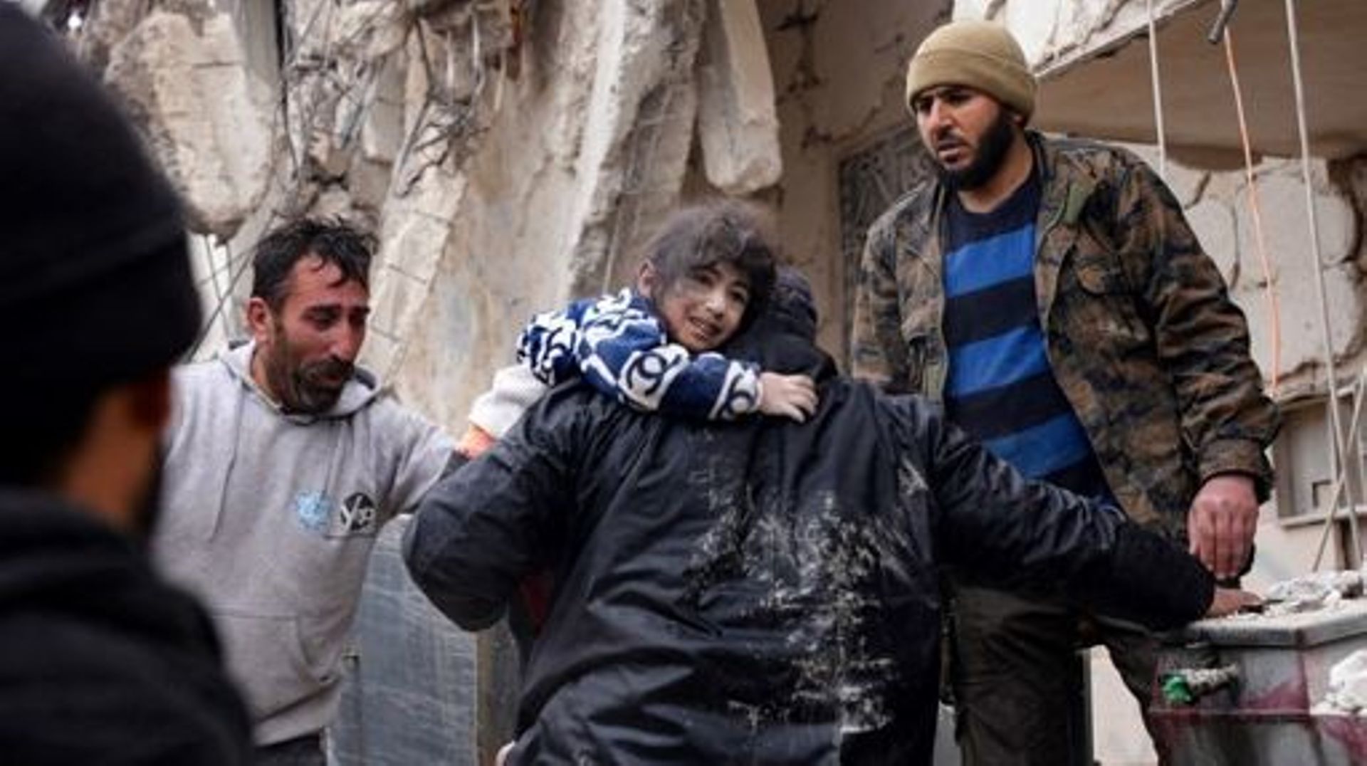 Des habitants récupèrent un petit enfant dans les décombres d'un bâtiment effondré à la suite d'un tremblement de terre dans la ville de Jandaris, dans la campagne de la ville d'Afrin, au nord-ouest de la Syrie, dans la partie de la province d'Alep tenue 