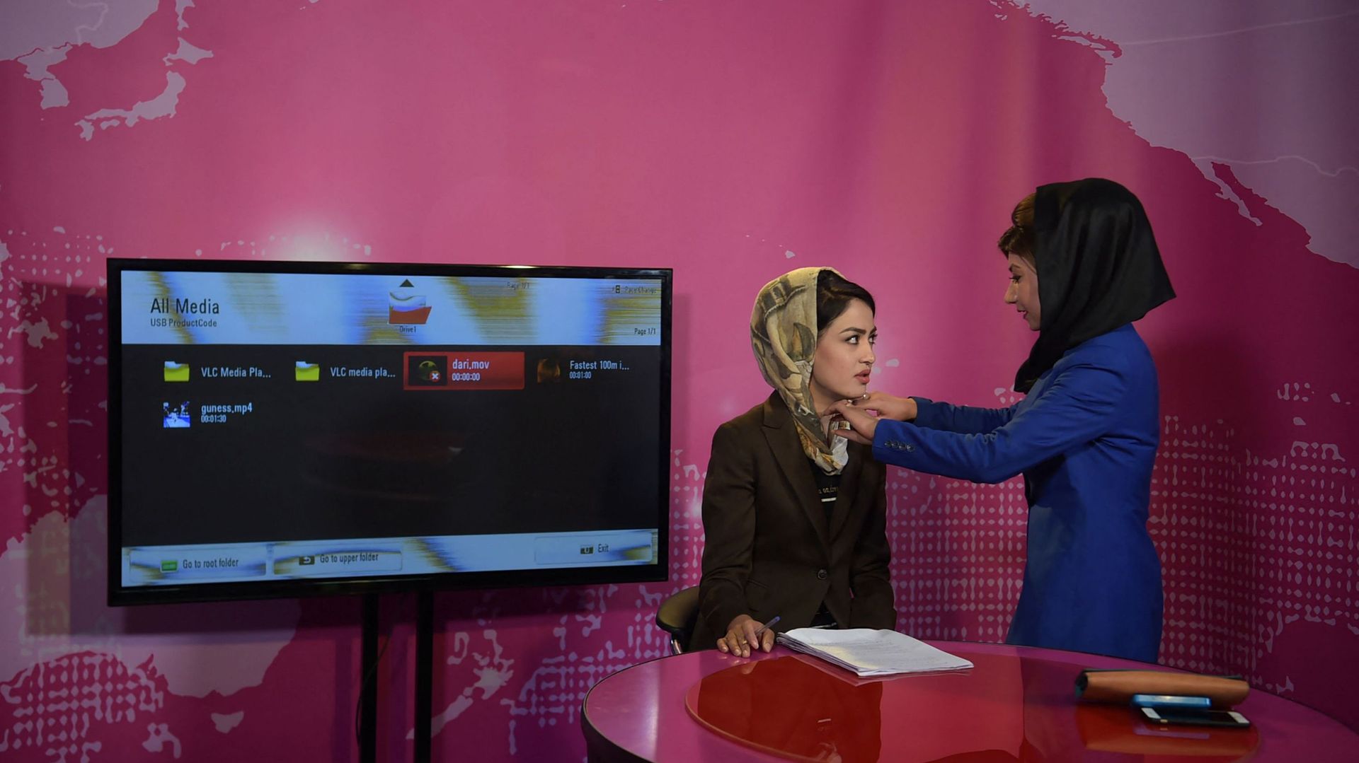 Sur cette photo prise le 24 mai 2017, une femme afghane ajuste le foulard d’une présentatrice (G) avant l’enregistrement à la station Zan TV (Women’s TV) à Kaboul.