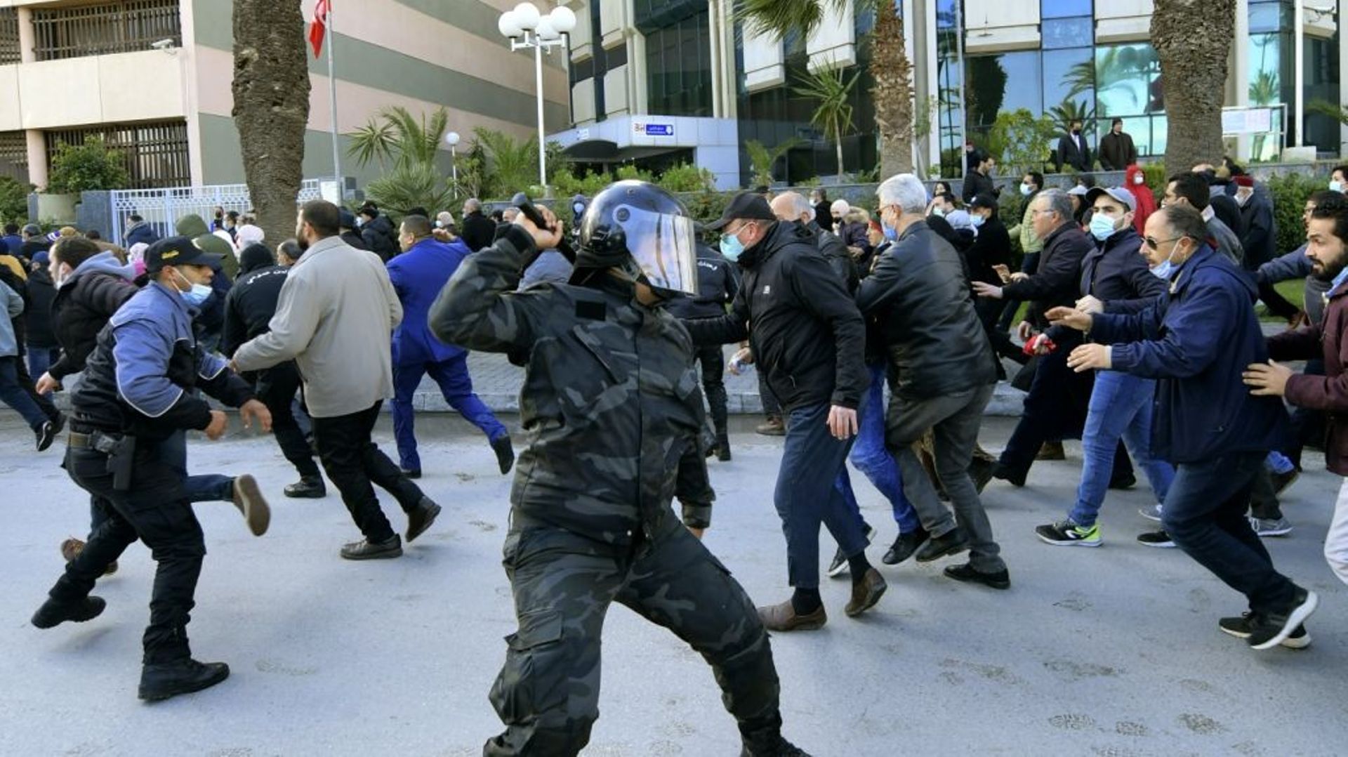 Un policier lève sa matraque pendant que des manifestants courent pour se protéger lors d’un rassemblement contre le président Kais Saied marquant le 11e anniversaire de la révolution tunisienne, le 14 janvier 2022 à Tunis