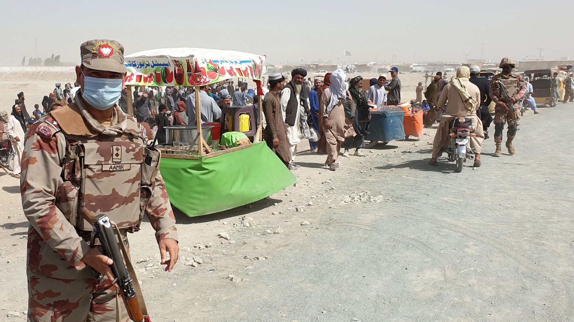 Un soldat de l’armée patrouille devant des personnes bloquées à la frontière de Chaman le 7 août 2021, après que les talibans ont pris le contrôle de la ville frontalière afghane lors d’une offensive rapide à travers le pays.