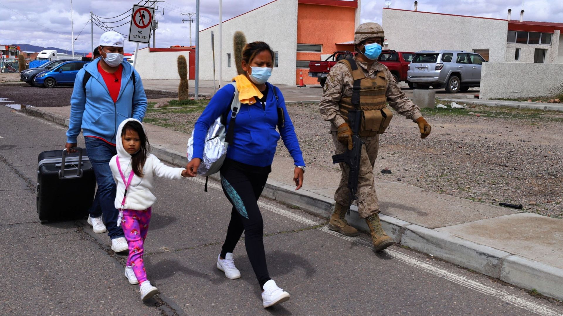 Un soldat chilien escorte des migrants vers les locaux de la police à Colchane, au Chili, à la frontière avec la Bolivie, le 15 février 2022.