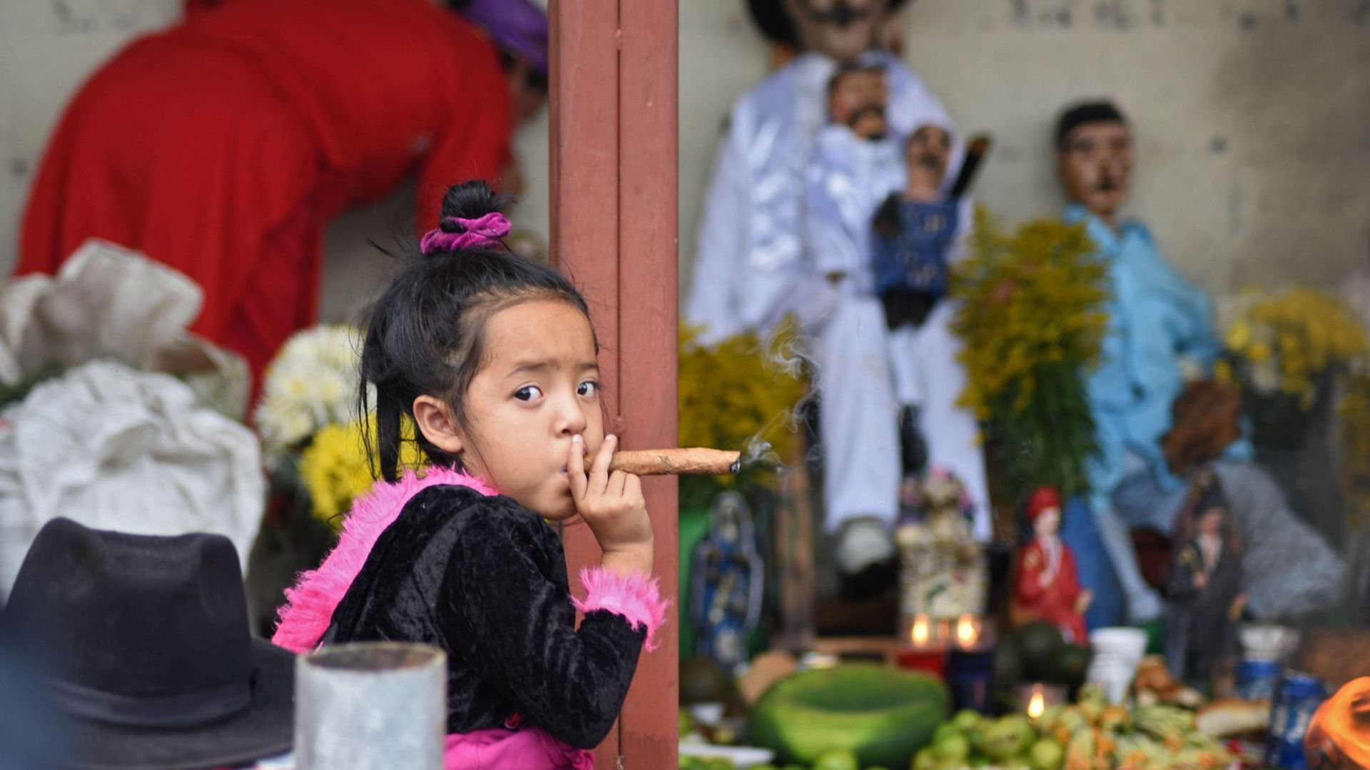 Une fillette de trois ans fume un cigare lors des célébrations du saint Simon à San Andres Itzapa, au Guatemala, le 28 octobre 2019. Des milliers de personnes pensent que le saint aide les gens à trouver du travail, à résoudre leurs problèmes familiaux et