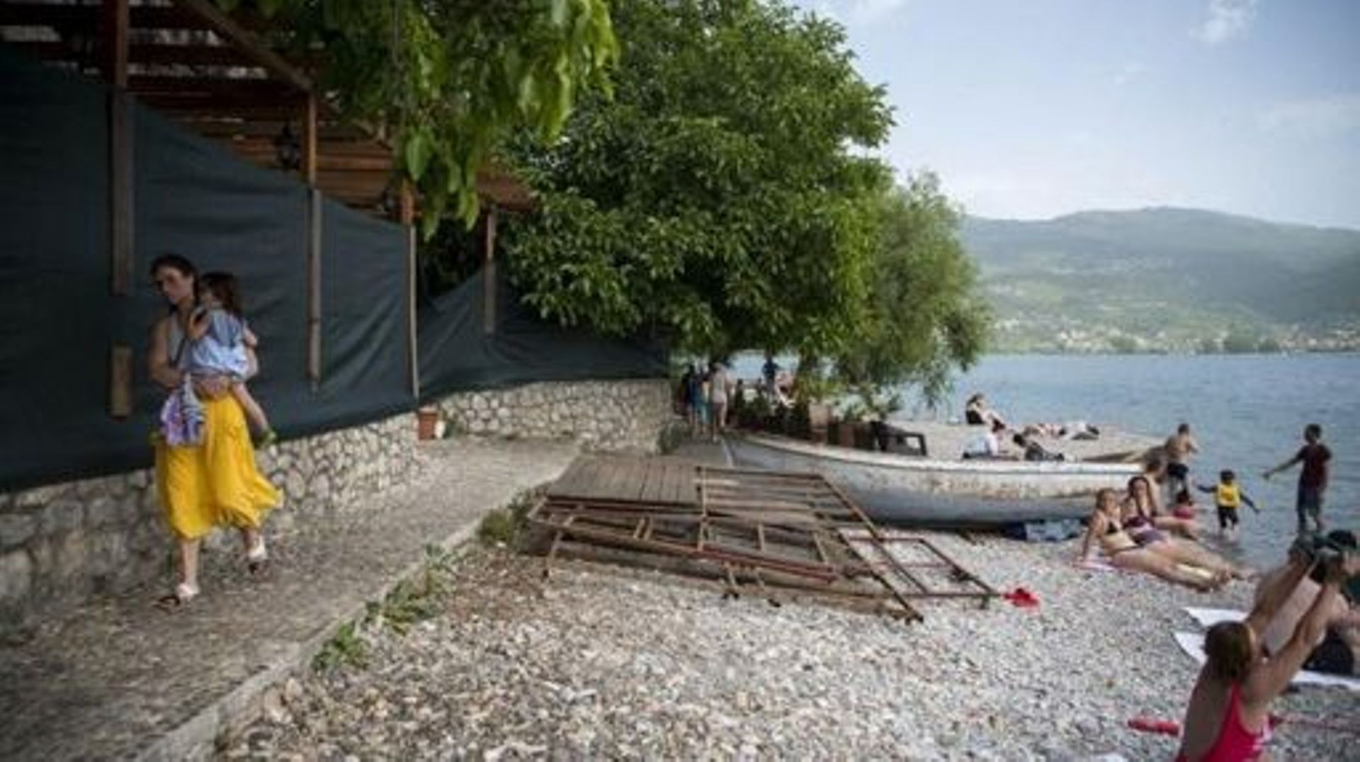Local residents sunbathe nearby rubbish left after the demolition of an illegal structure on the shore of the Lake Ohrid, southwestern of the Republic of North Macedonia, on June 22, 2021. UNESCO has said the site, which straddles the border between North