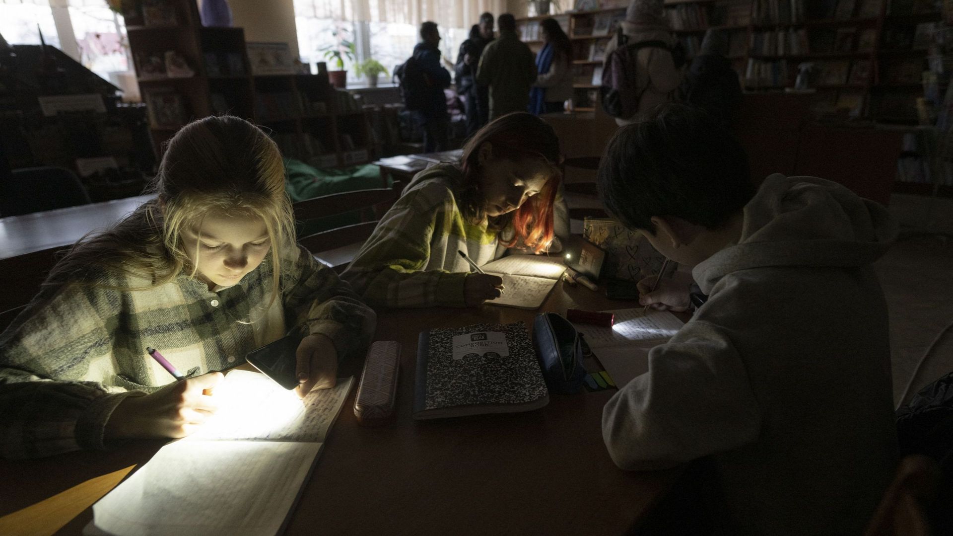 A Kiev, des enfants lisent en s’aidant de lampes de poche