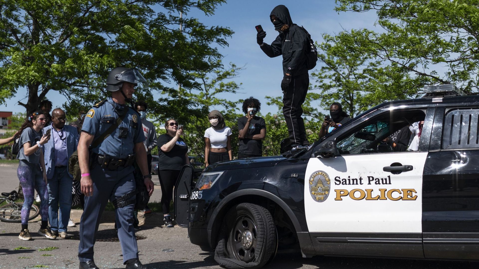 Un manifestant filme un policier alors qu’il se trouve sur une voiture détruite le 28 mai 2020 à St. Paul, Minnesota.
